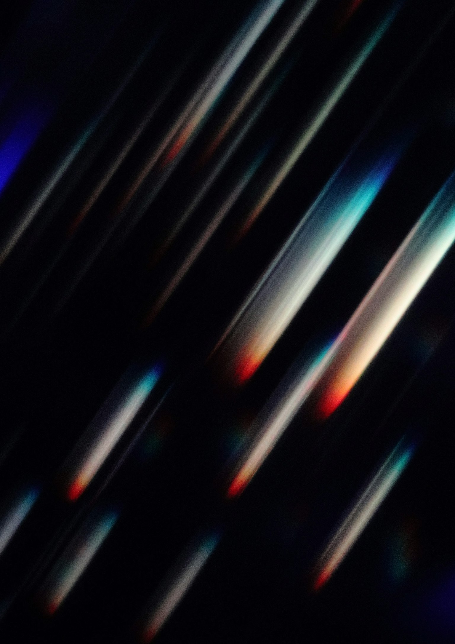 Imagen abstracta con rayas de luz coloridas fluyendo diagonalmente sobre un fondo oscuro