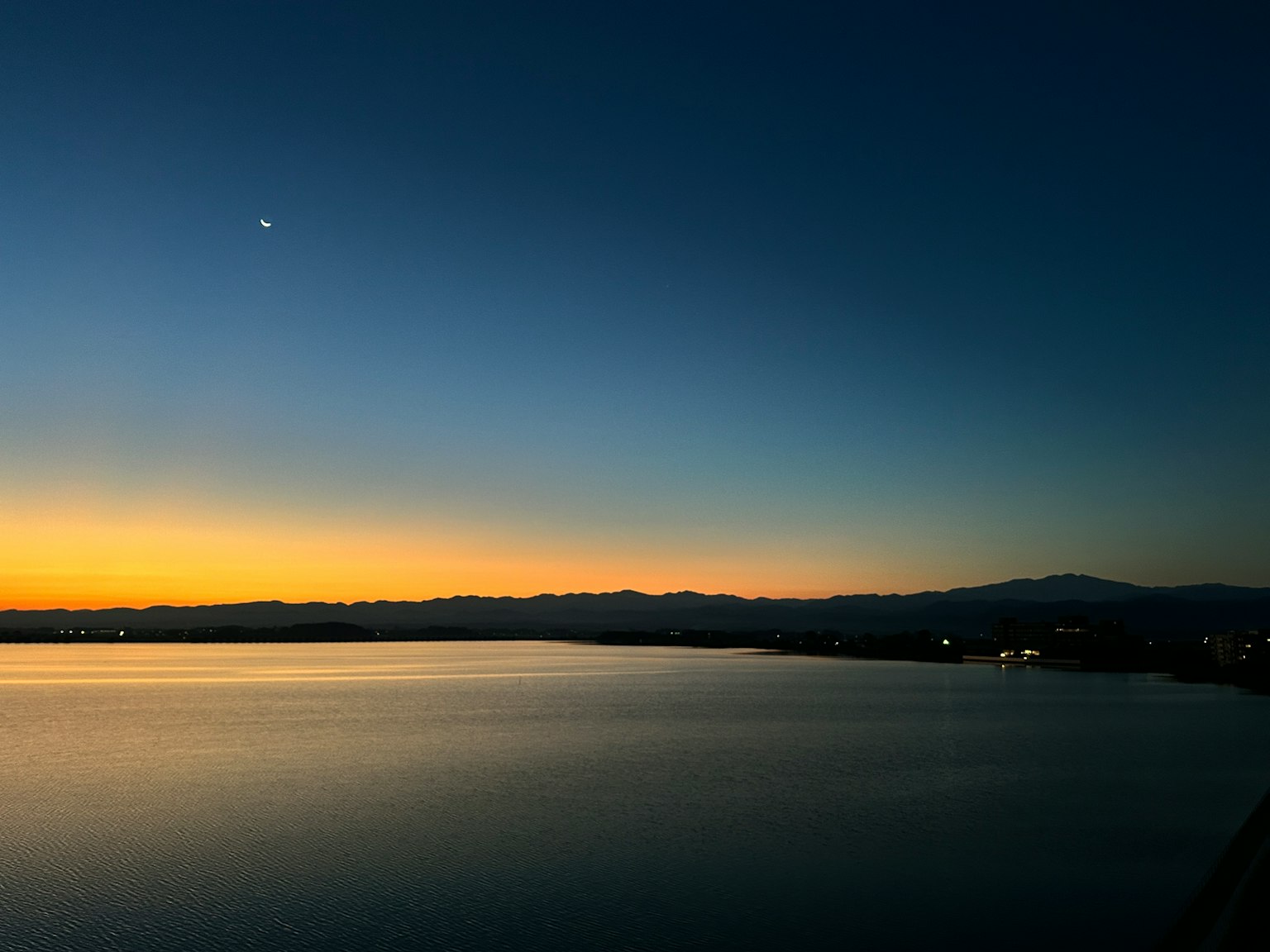Schöne Seelandschaft bei Sonnenuntergang mit silhouettierten Bergen