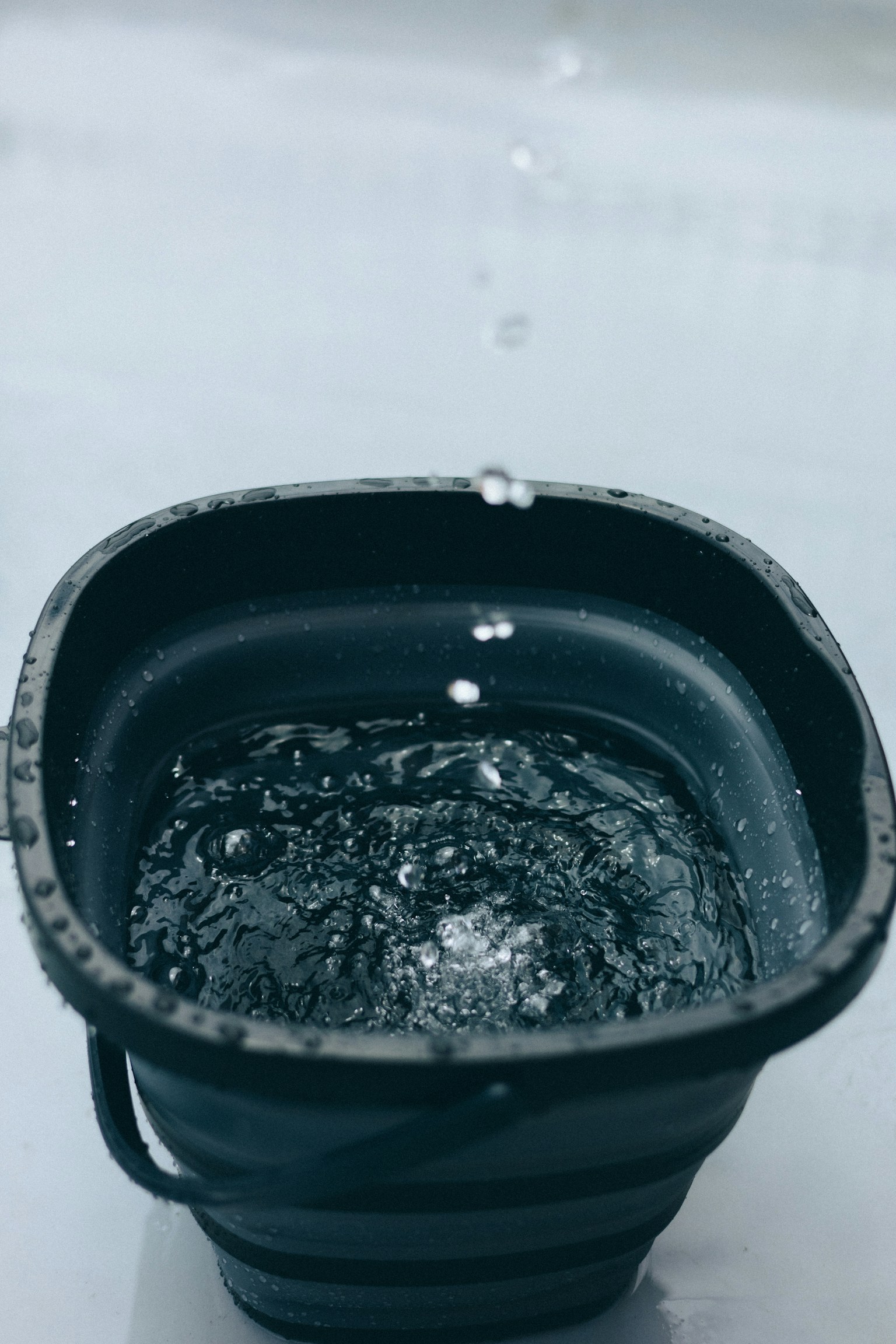 一个装满水的黑色桶，水滴正在掉入其中