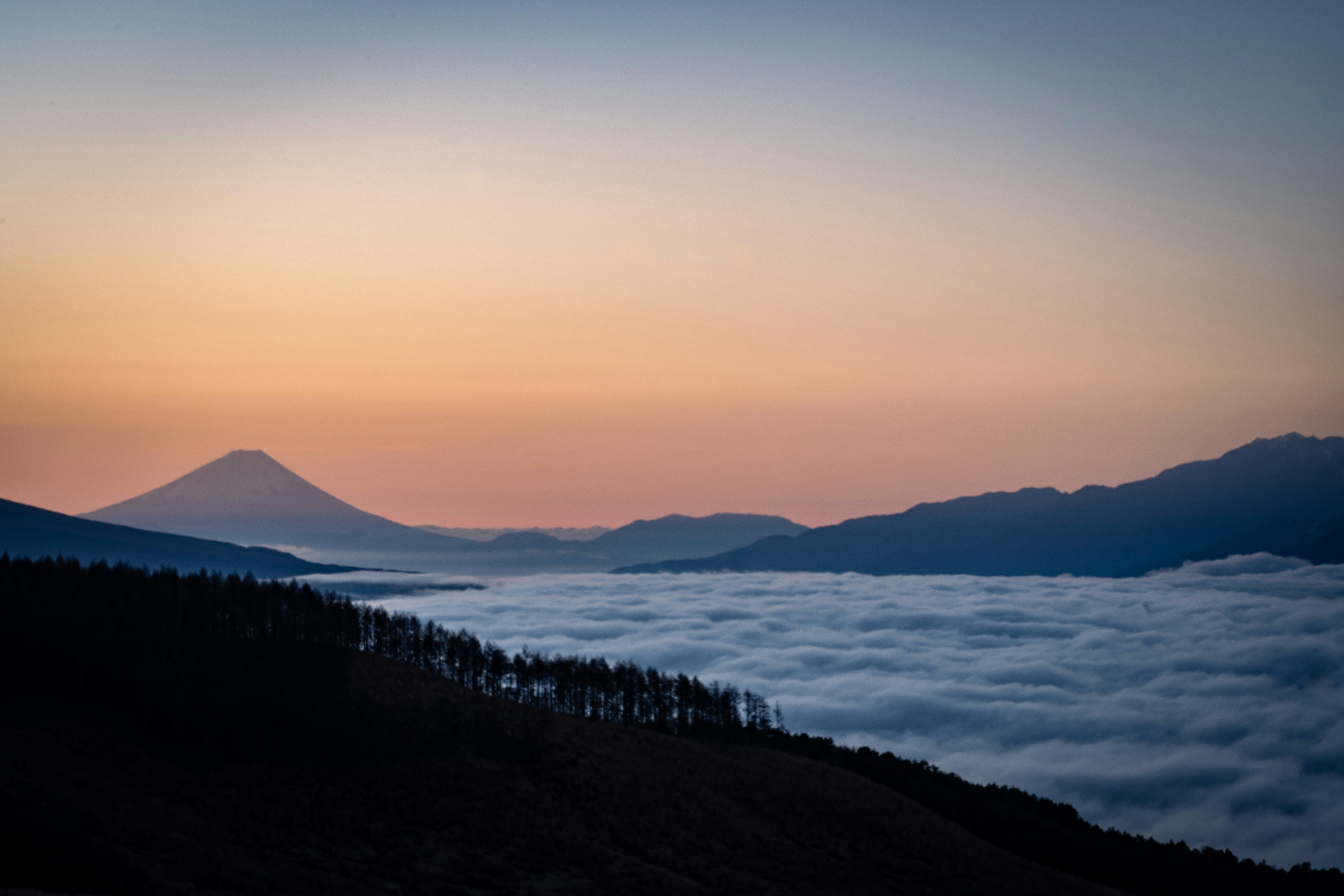 Vista escénica de montañas rodeadas de un mar de nubes al atardecer