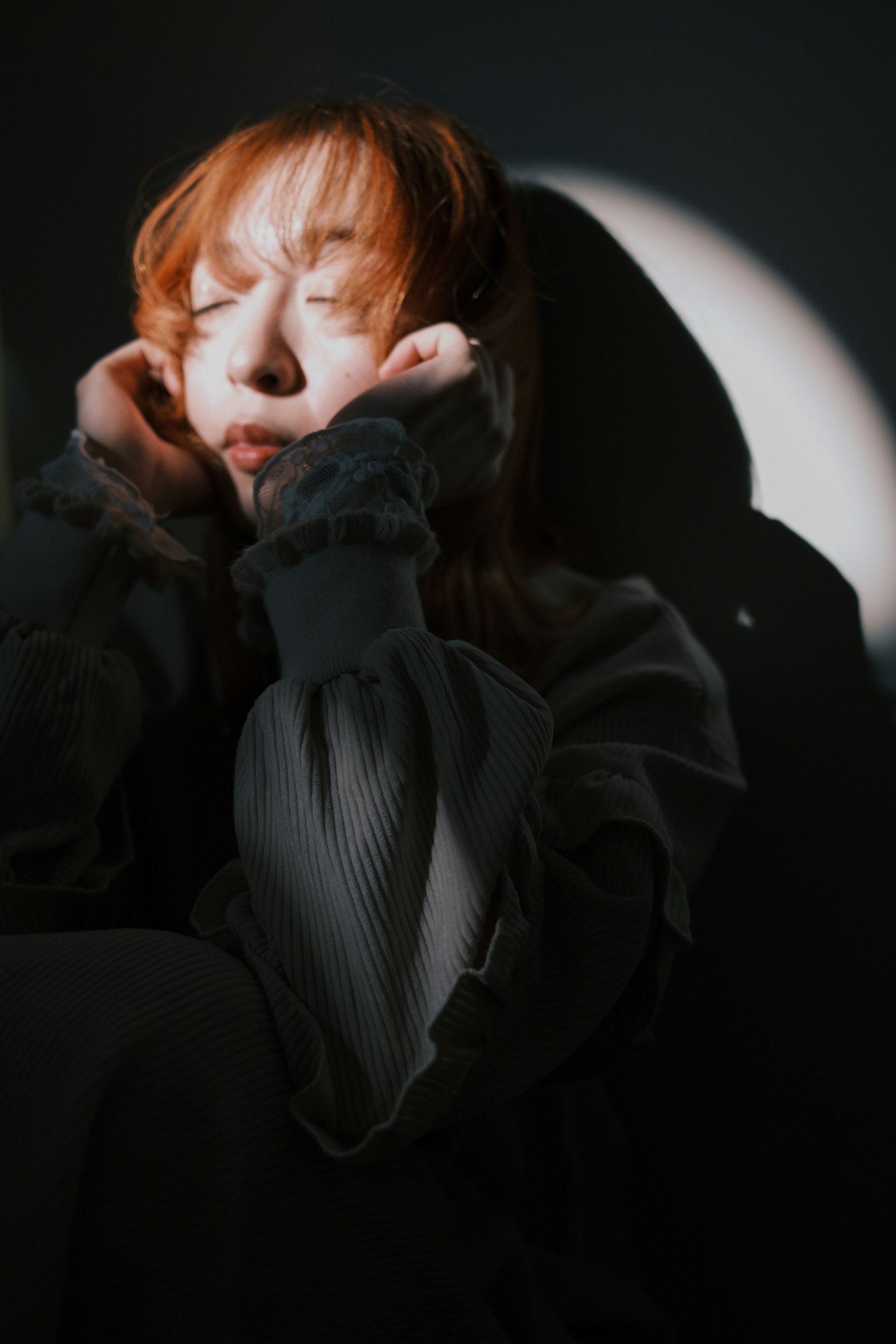 女性が目を閉じているシルエットの写真 背景に月のような光がある