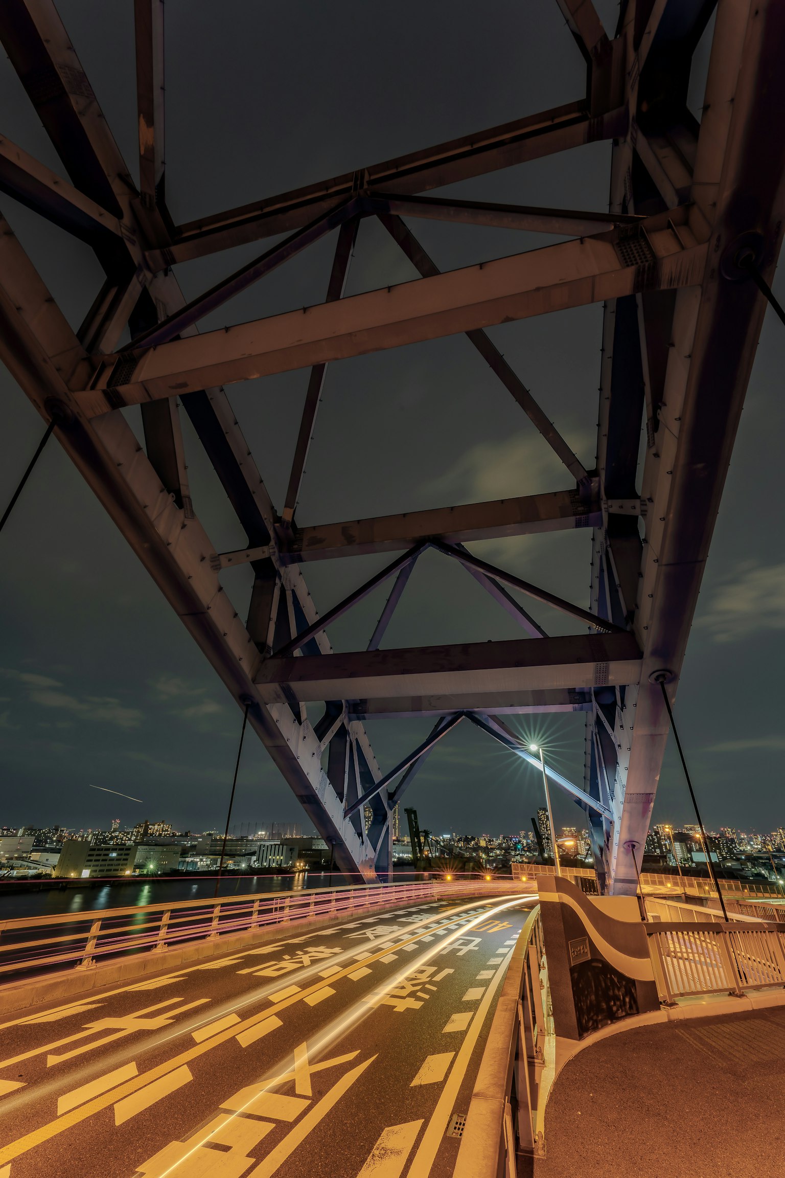 夜间桥梁的钢结构和背景中的城市灯光