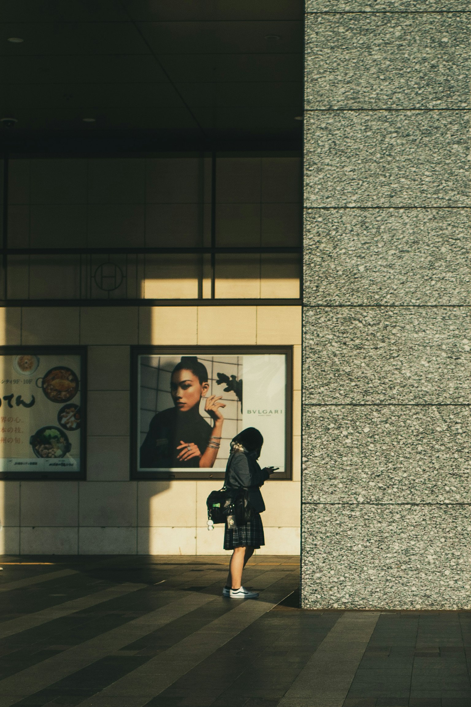 Une femme adossée à un mur avec une grande affiche dans un cadre urbain