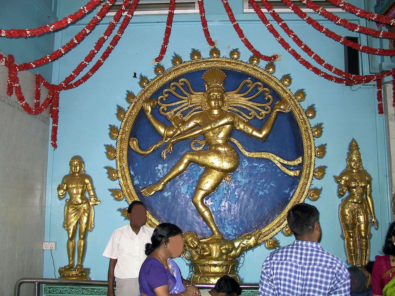 Interno di un tempio vivace con una statua dorata di Lord Shiva su sfondo blu e altre divinità