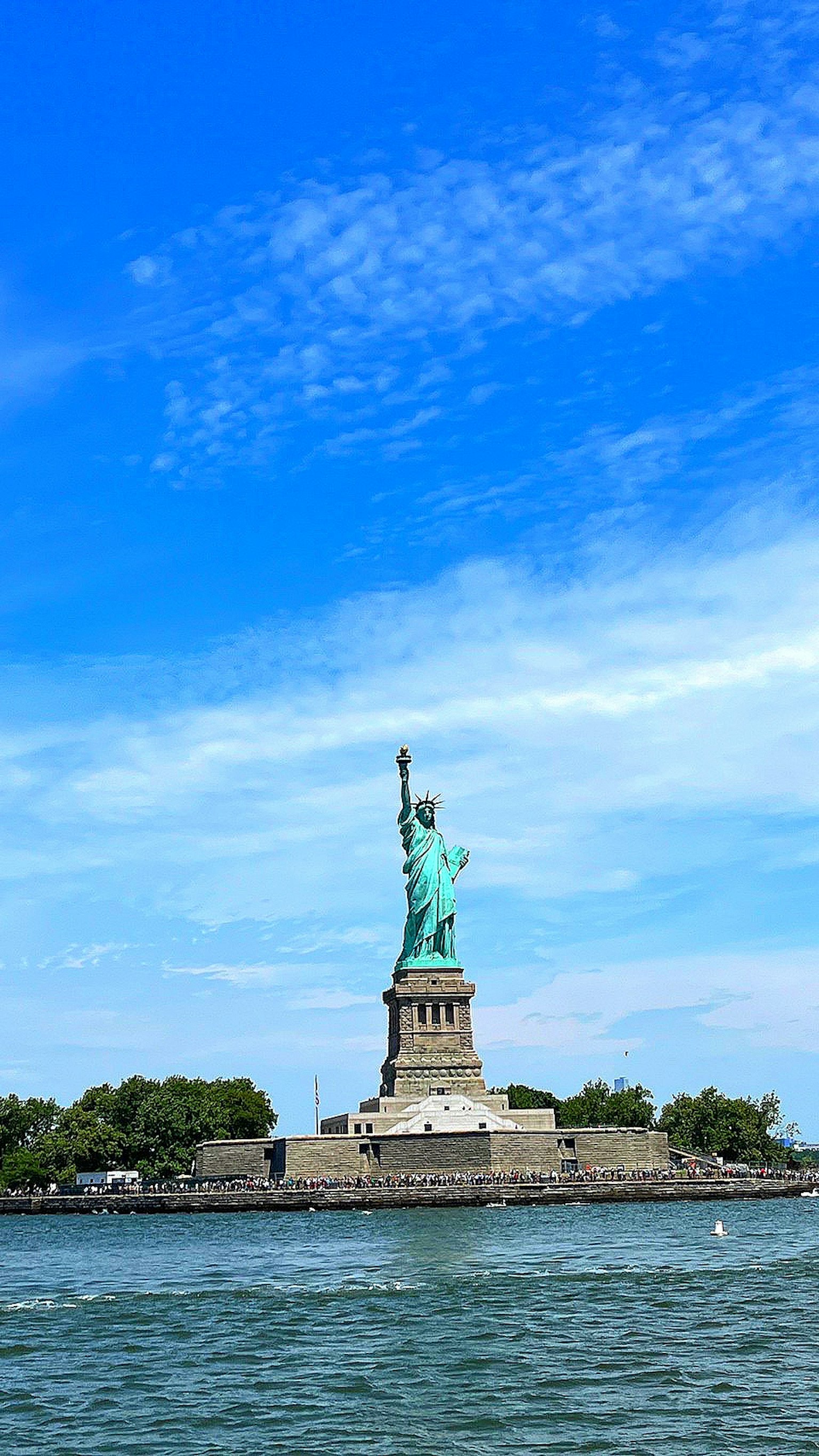 Freiheitsstatue unter einem blauen Himmel mit umliegendem Wasser