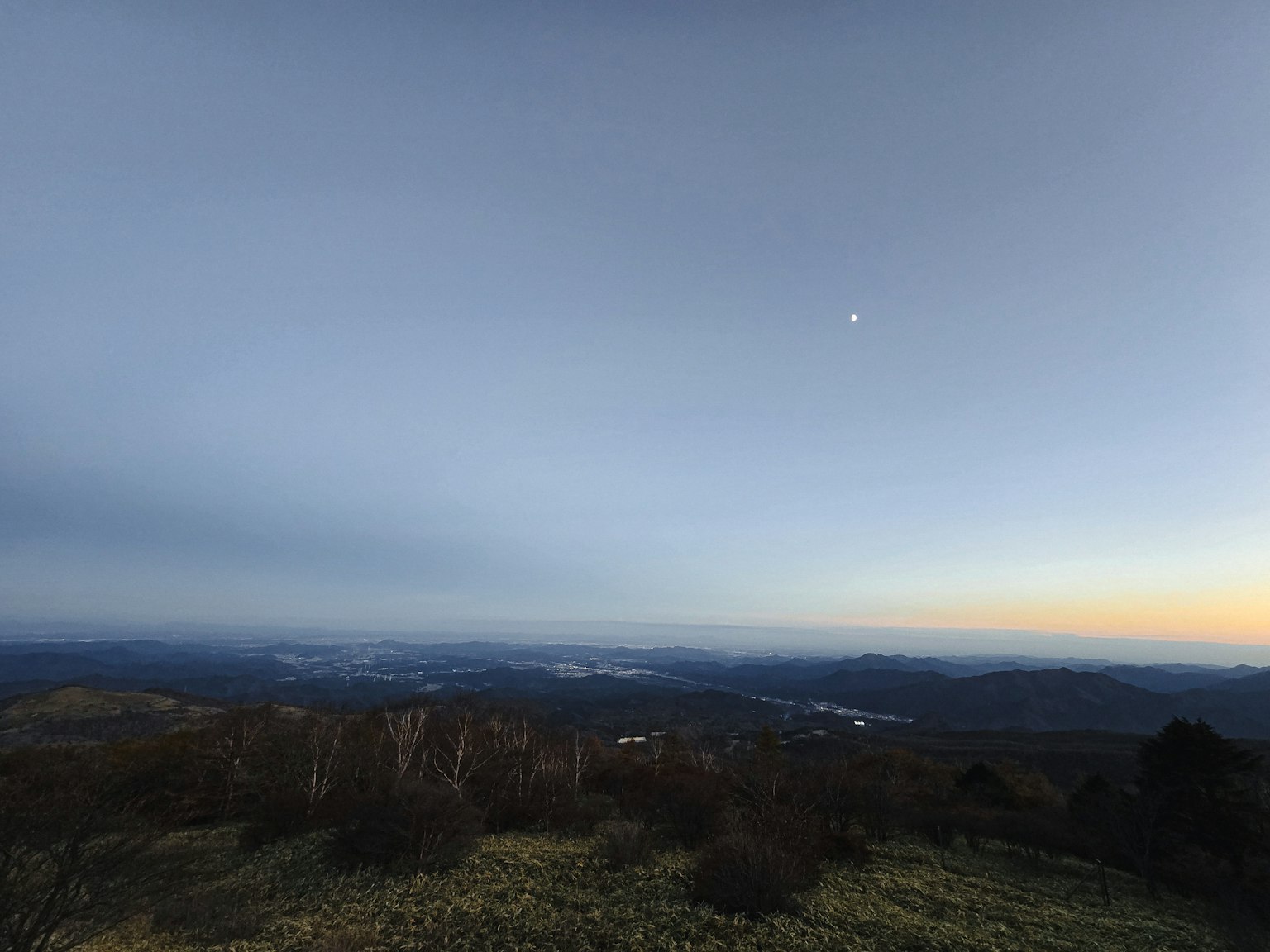 Paesaggio montano con cielo blu sfumato e luna al crepuscolo