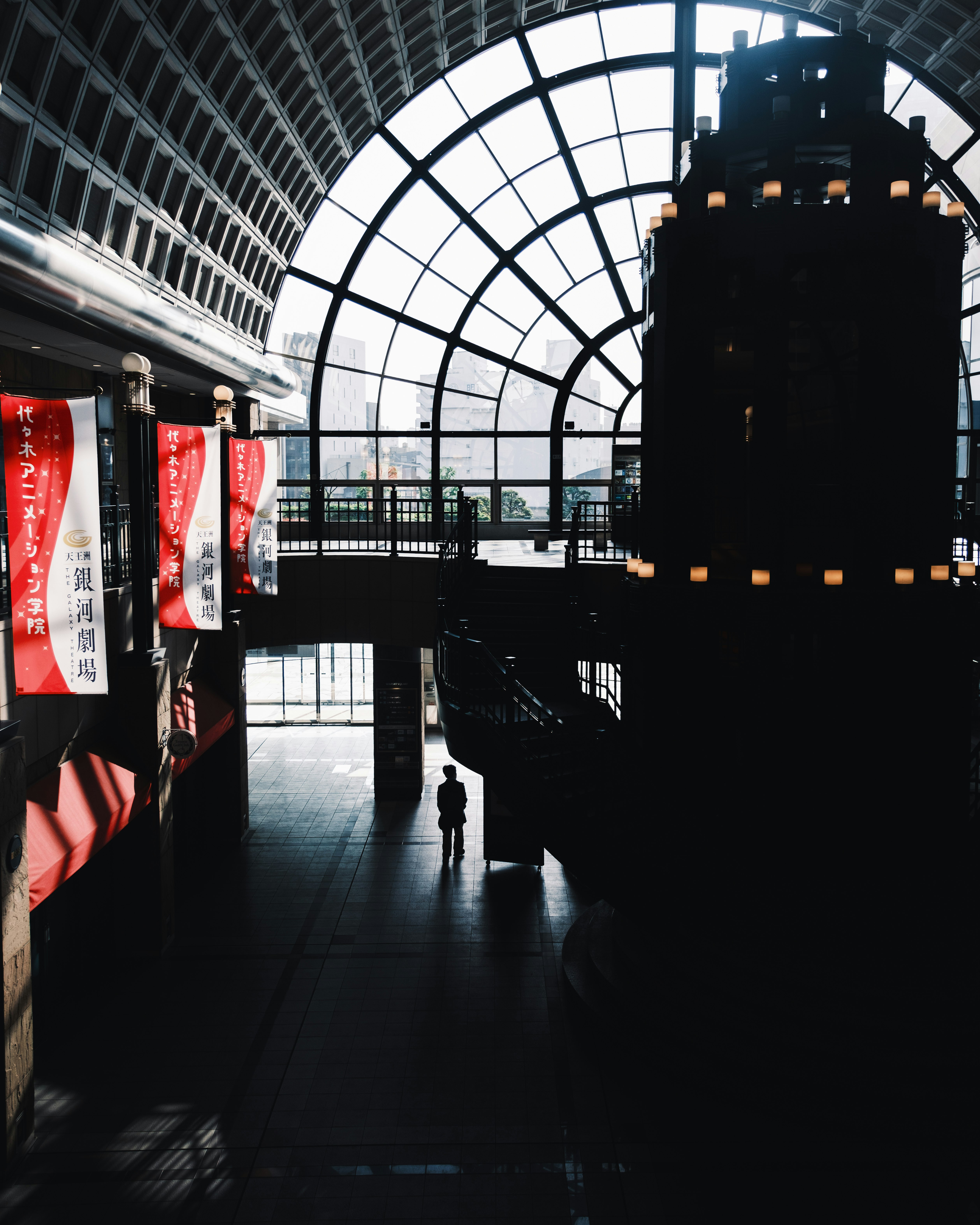 passage inside a glass-arched station with red banners