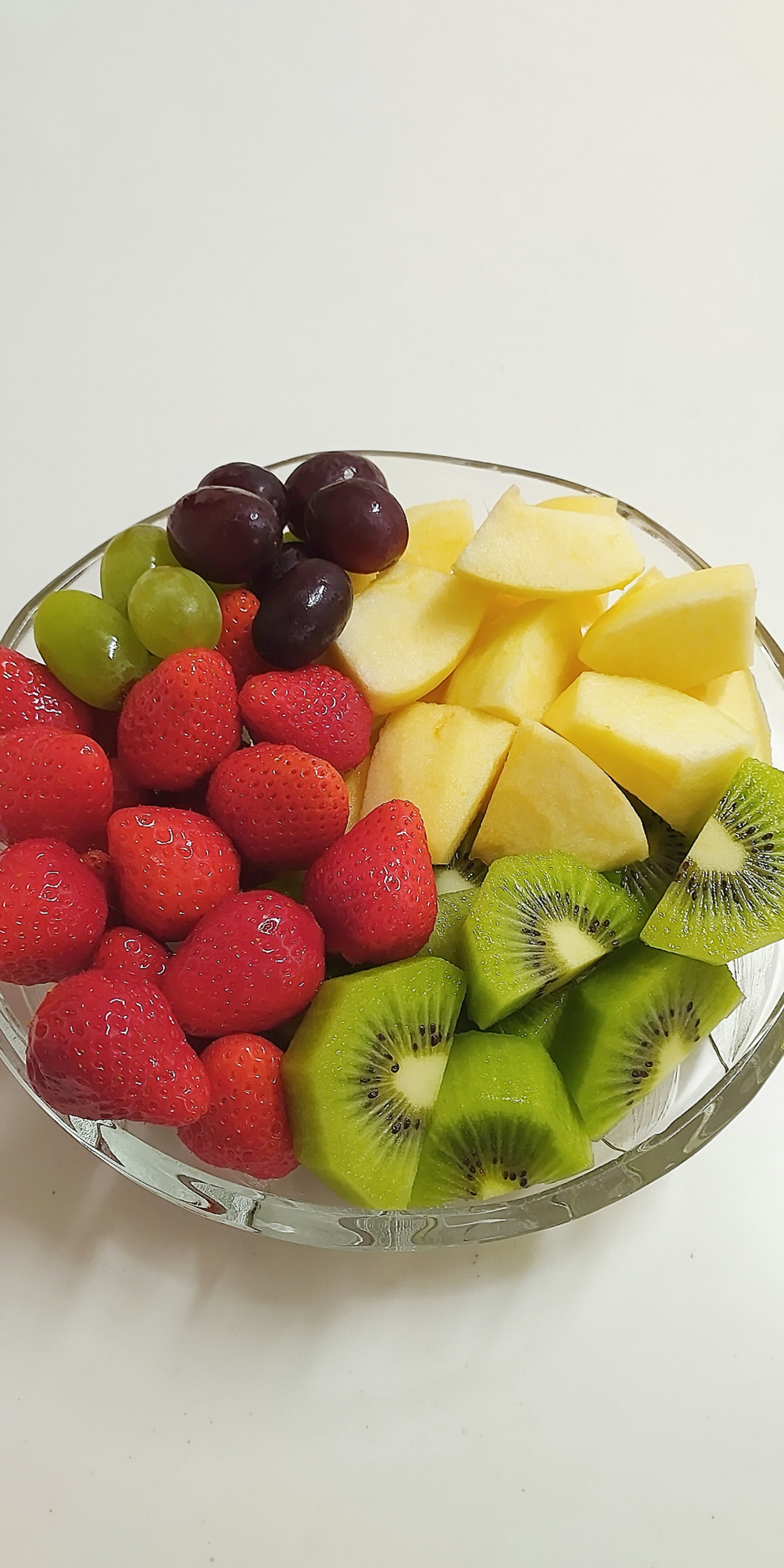 Un assortiment coloré de fruits dans un bol avec des fraises raisins ananas kiwi