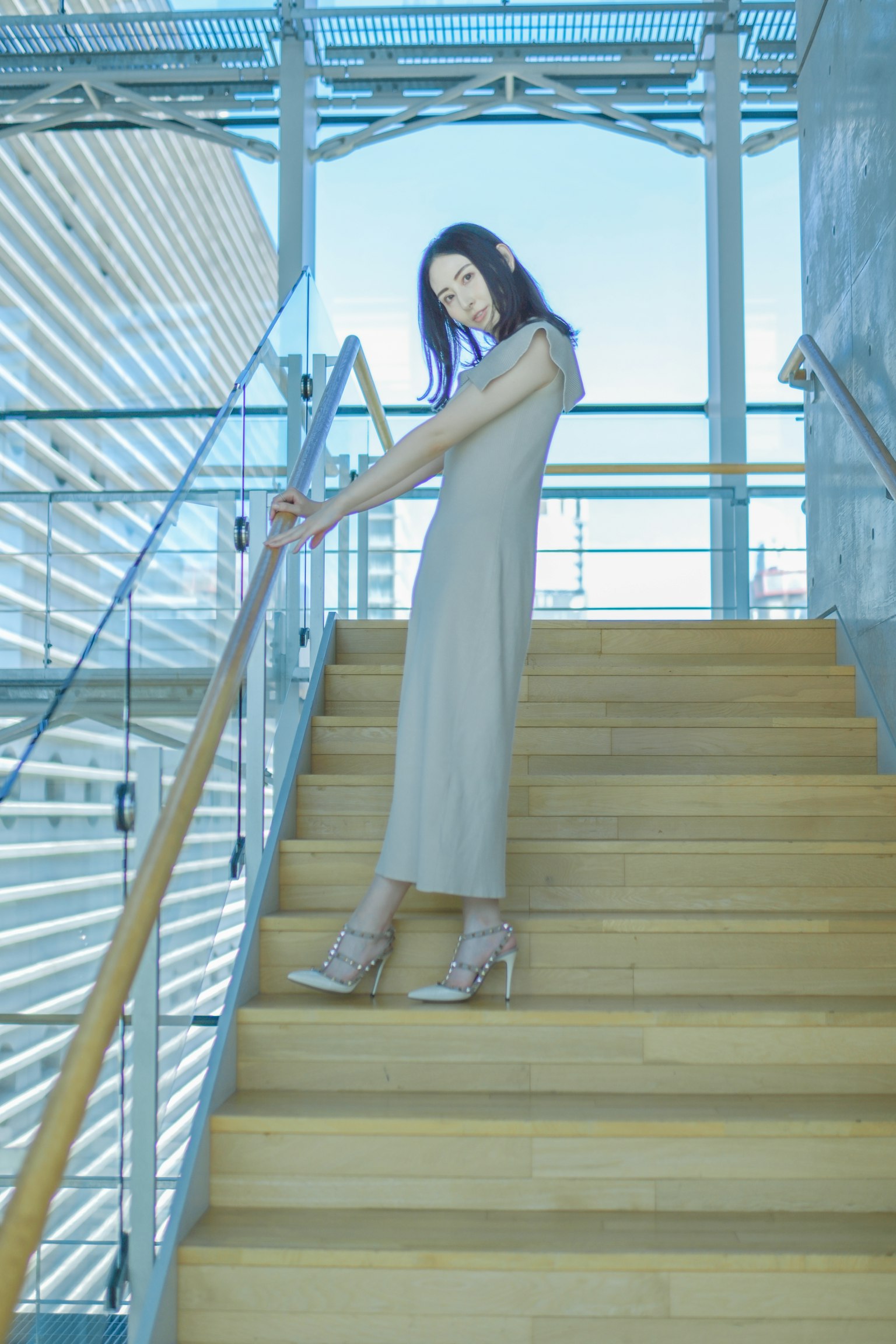 站在楼梯上的女性 现代建筑背景 米色连衣裙和高跟鞋