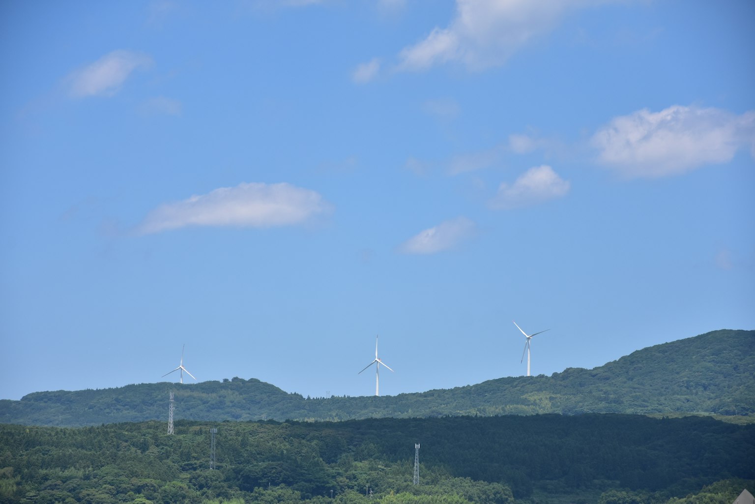 Wind turbines on green hills under a blue sky