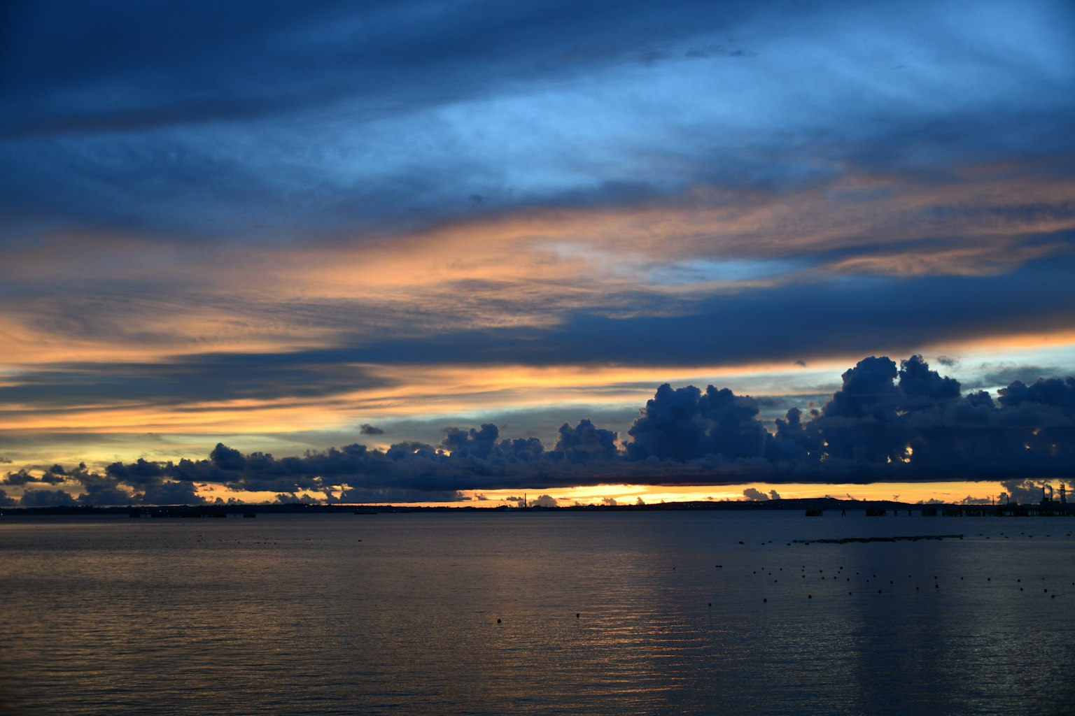 Sunset over the ocean with blue sky and orange clouds