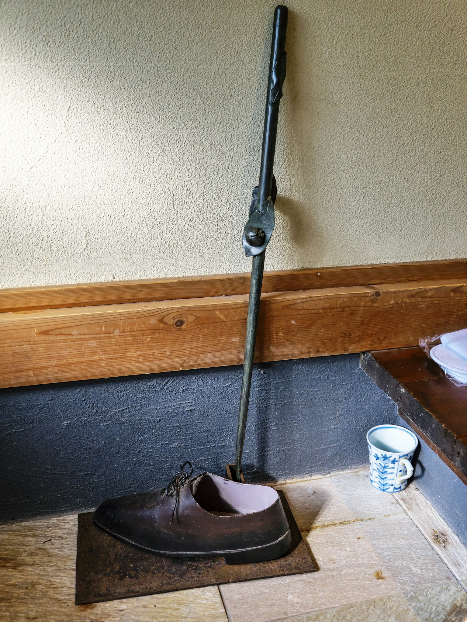 Cucchiaio di metallo a forma di scarpa appoggiato al muro