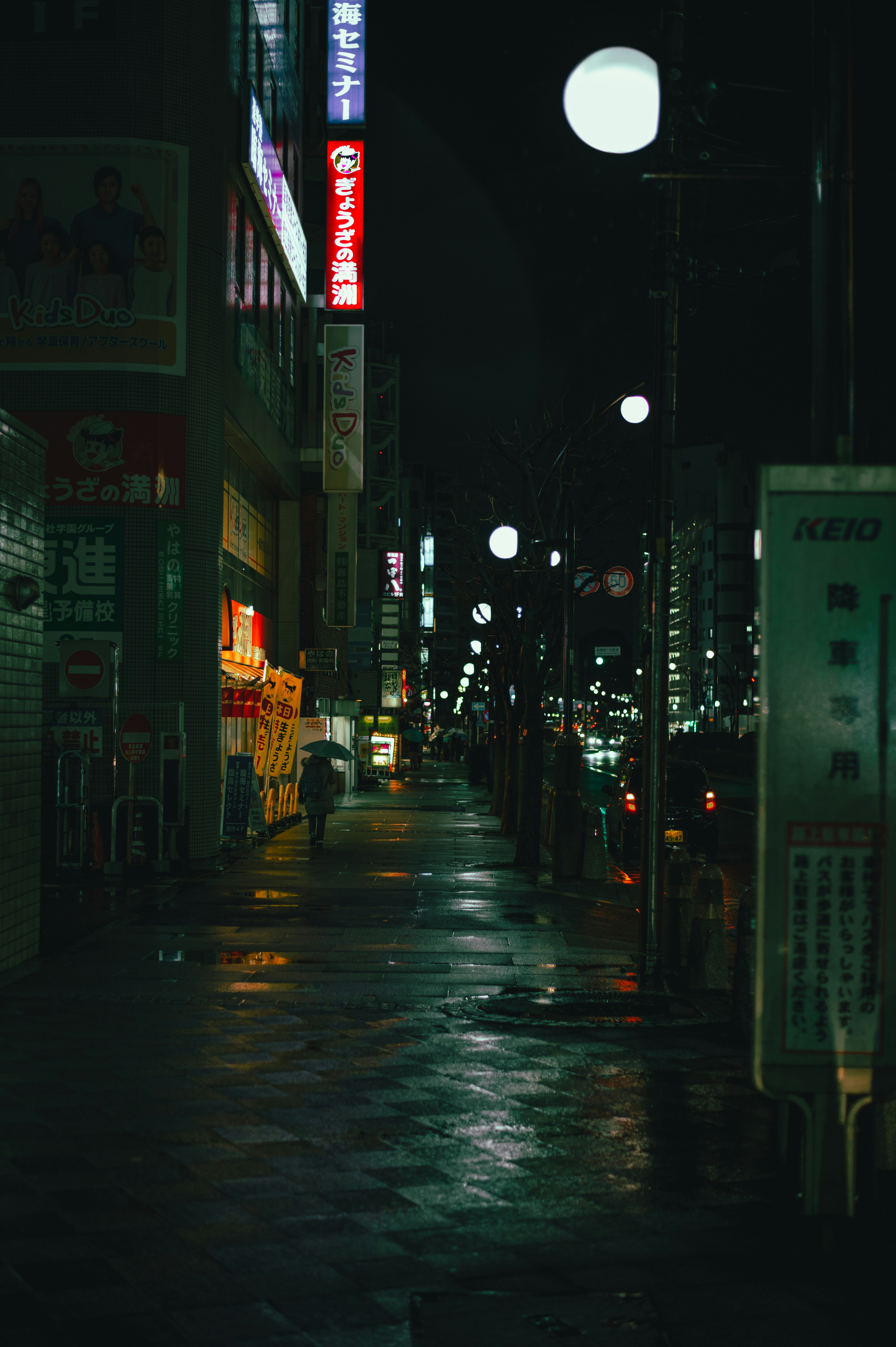 雨上がりの夜にネオンがにじむ狭い路地の街並み