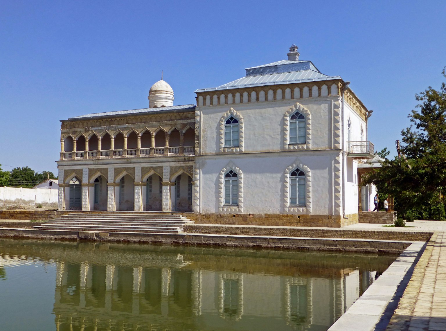 Un bâtiment blanc avec un étang montrant un style architectural traditionnel