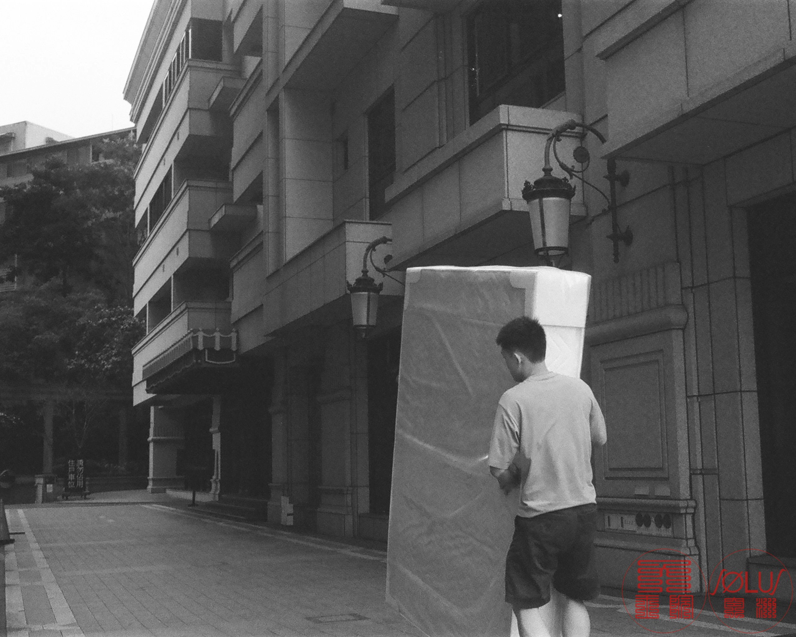 台北の路地で布をかぶせた荷物を運ぶ人物の後ろ姿