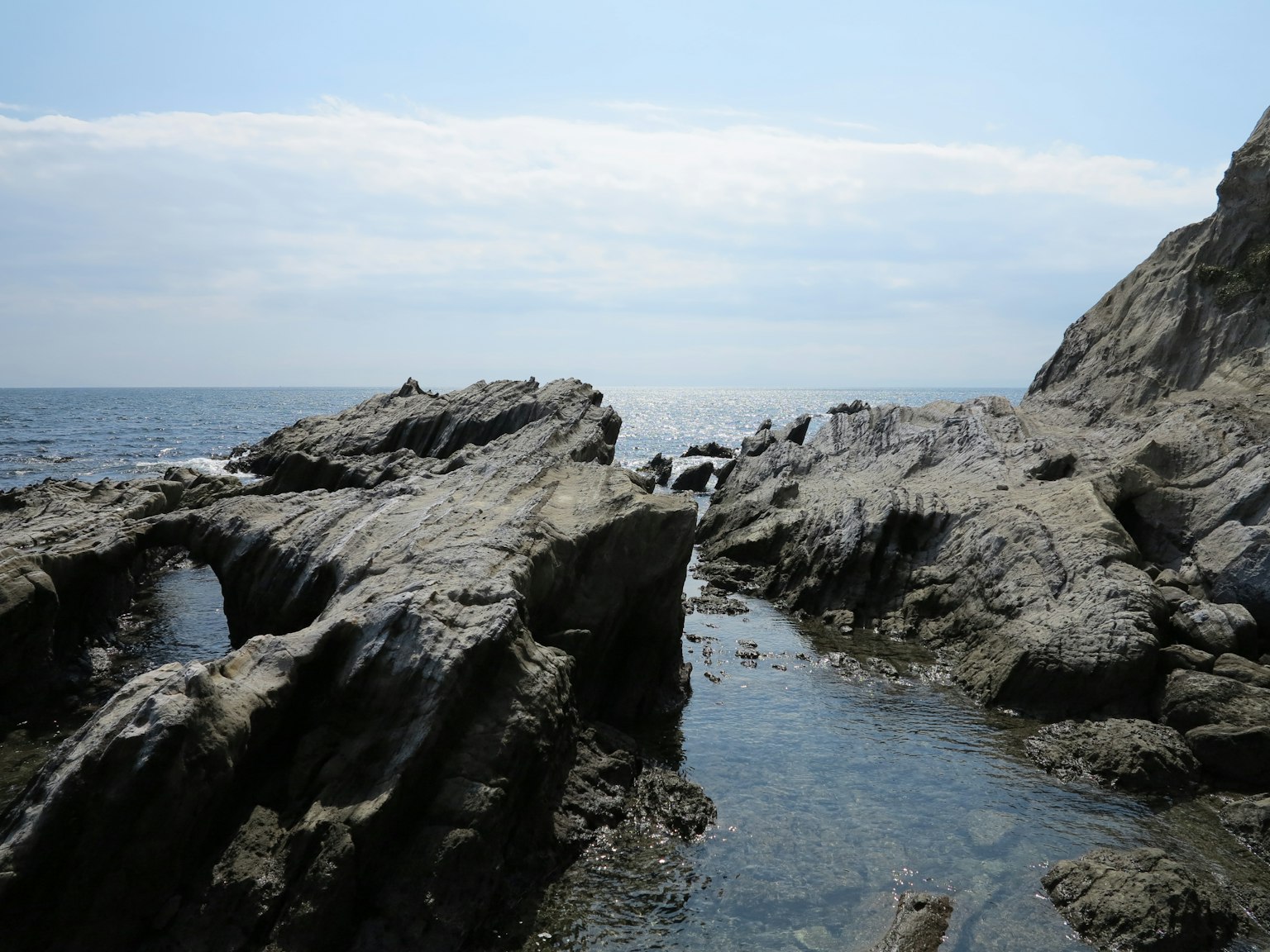 Vista costera con mar azul y costa rocosa bajo un cielo tranquilo