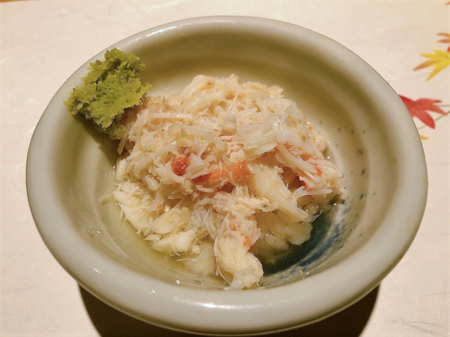 Mangkok kecil berisi sashimi ikan putih yang disuwir disajikan dengan wasabi