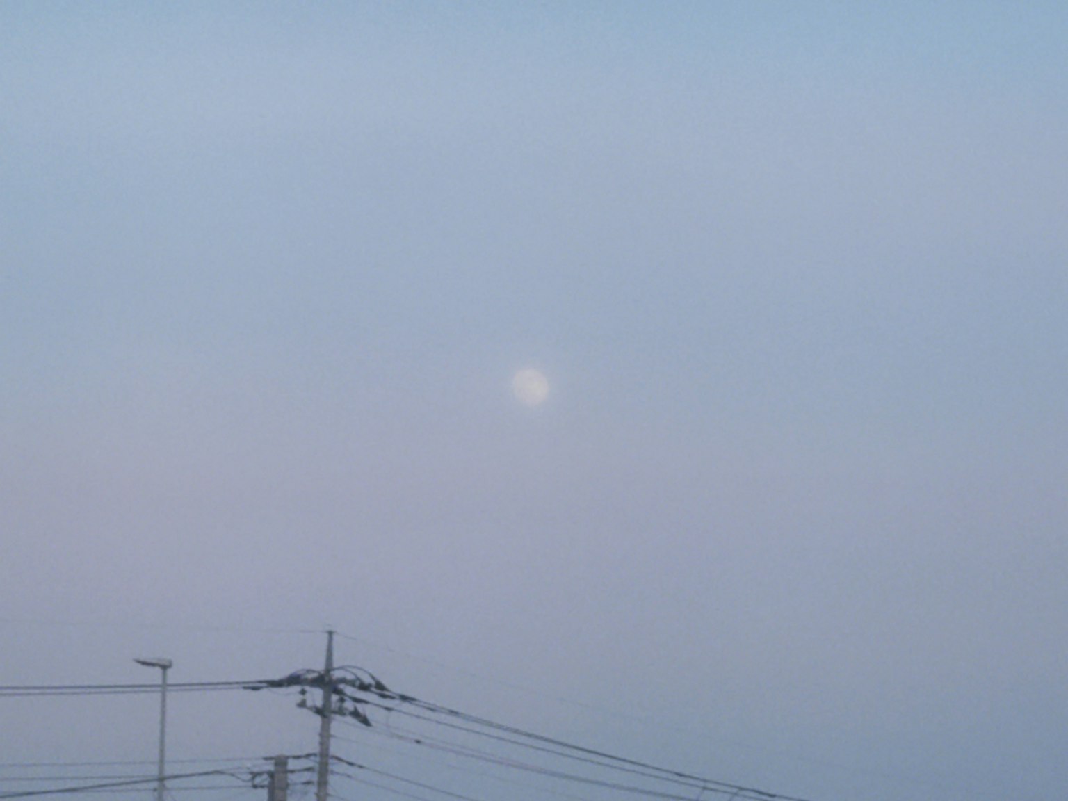 Langit sedikit mendung dengan bulan terlihat dan kabel listrik
