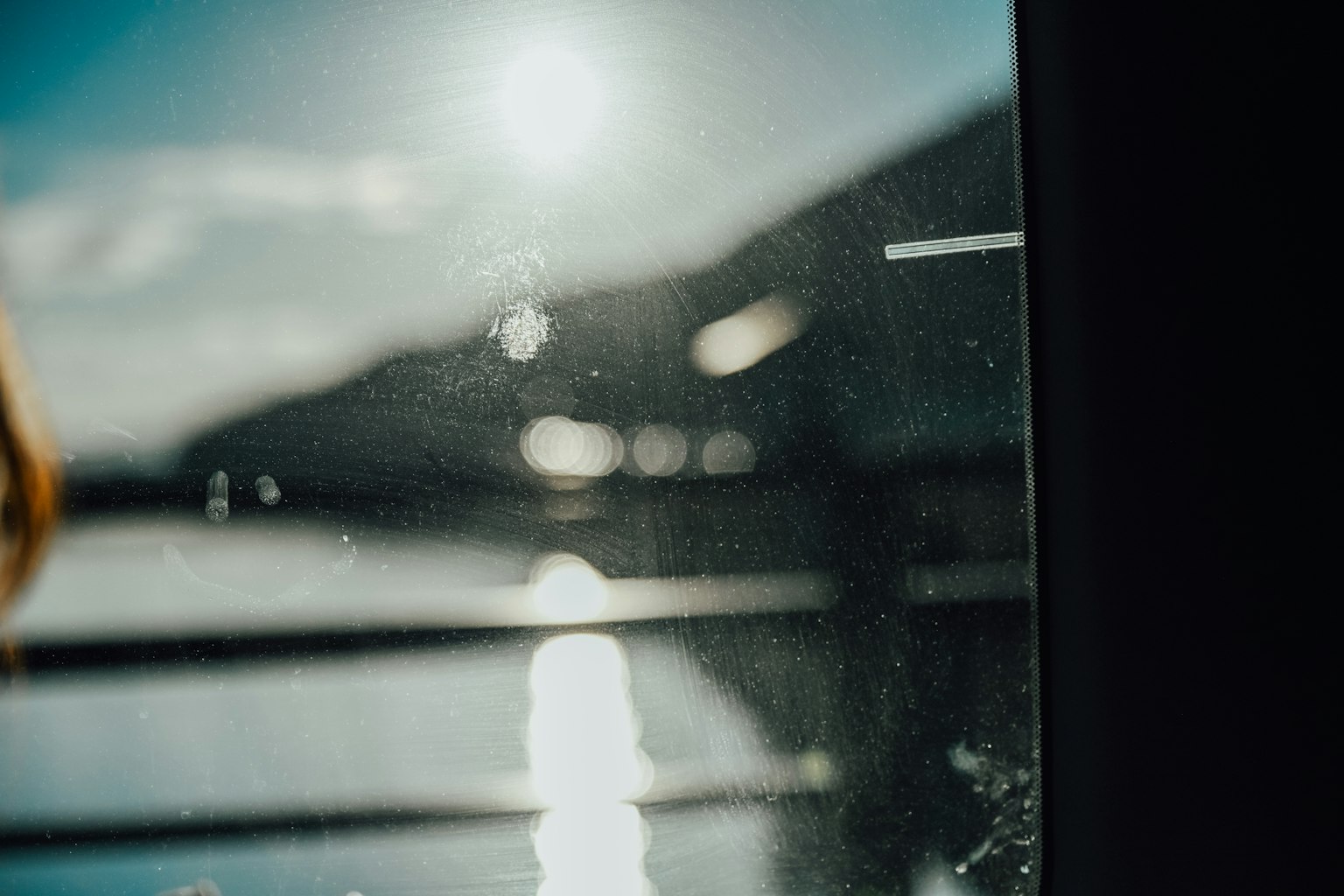 View of water surface and mountains through a window with blurred background and light reflections
