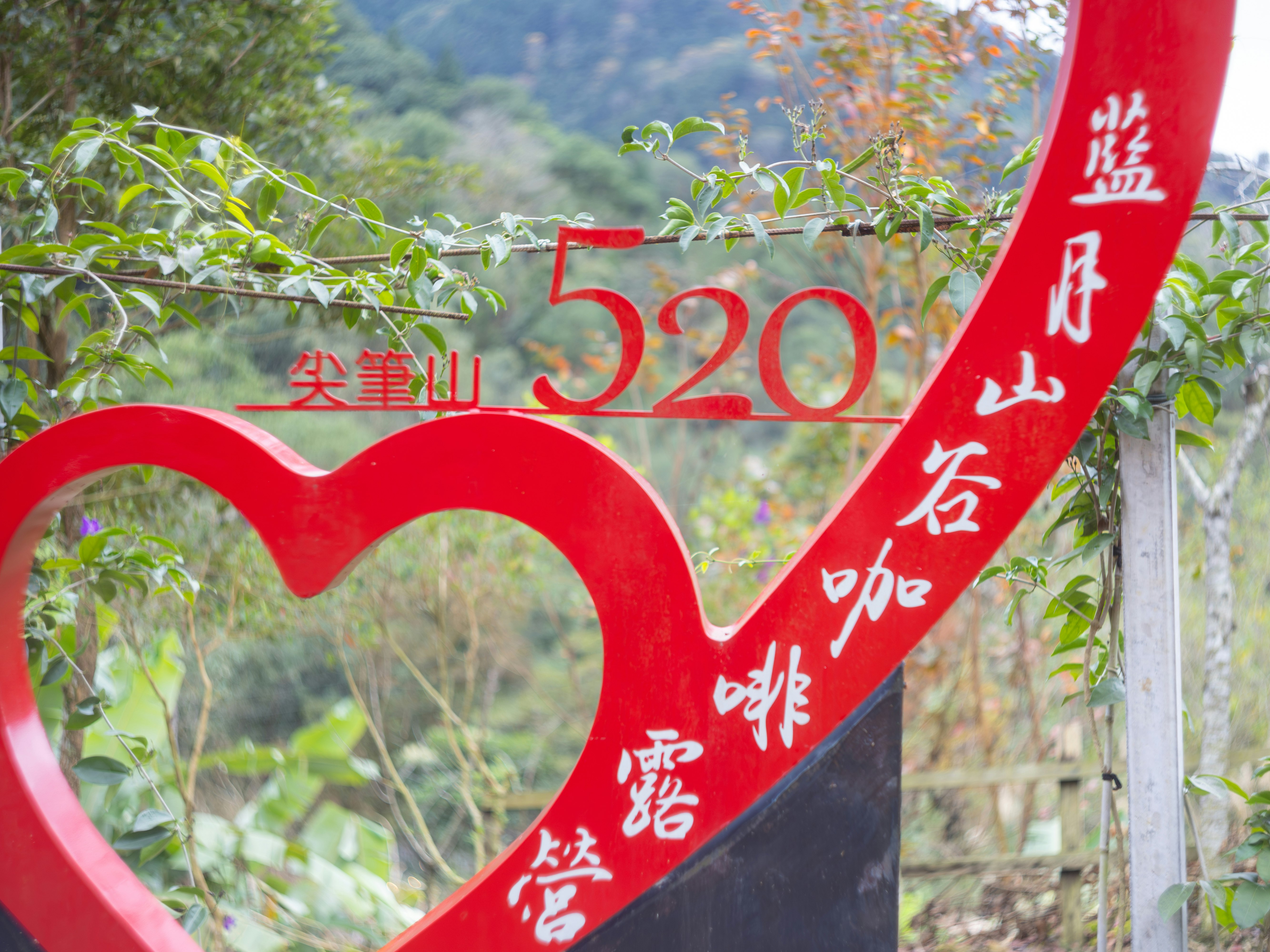 山の景色を背景にした赤いハート型の看板と旗