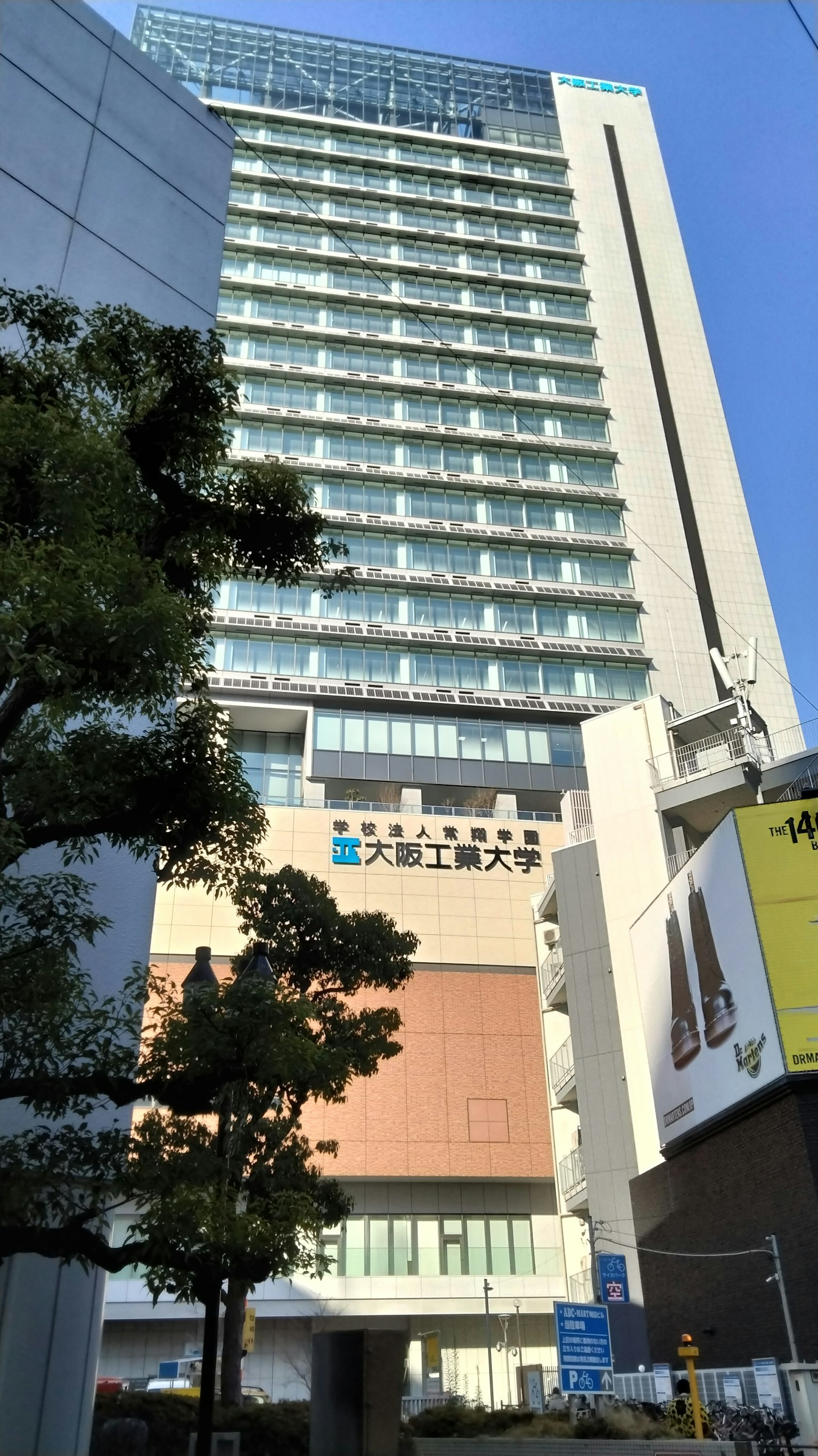 Fachada de un edificio alto bajo un cielo azul con árboles alrededor