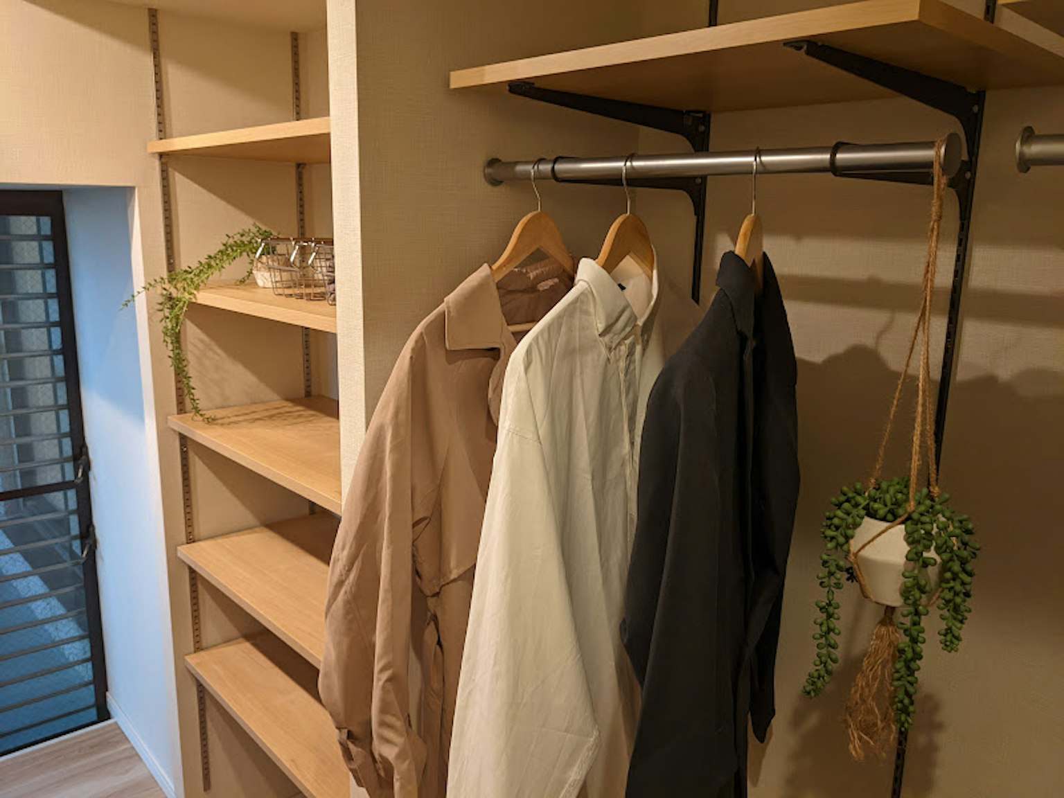 Interior de un armario simple con ropa beige, blanca y negra colgada