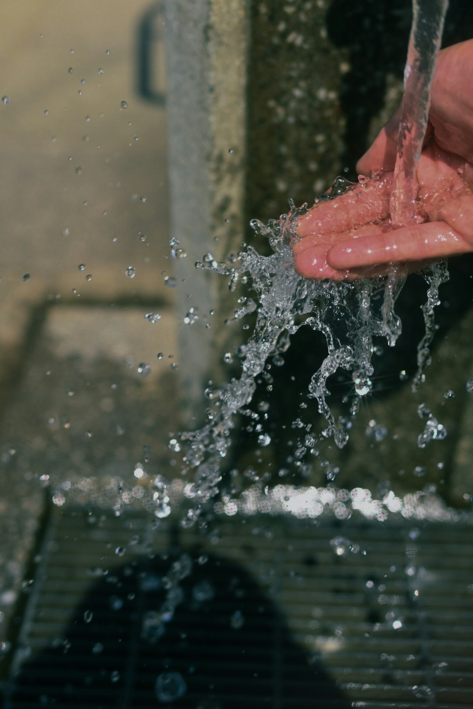 A person catching water in their hand with splashes visible