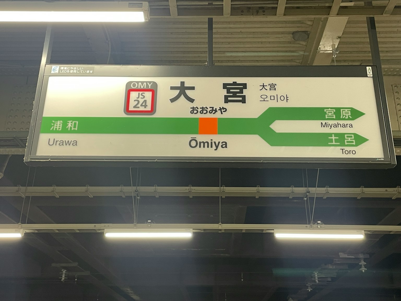 Papan arah di Stasiun Omiya dengan desain hijau dan teks dalam bahasa Jepang dan Inggris