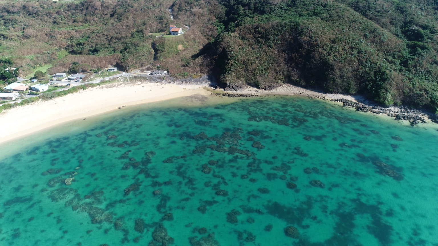 Vista aérea de una hermosa playa rodeada de agua azul y arena blanca
