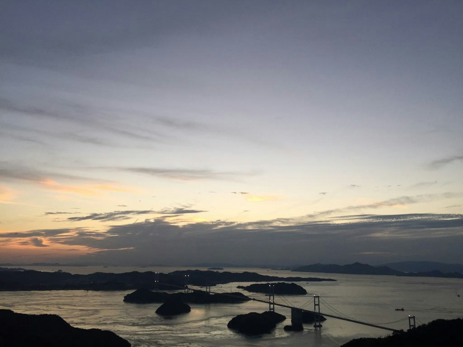 Panoramablick auf einen Sonnenuntergang über dem Ozean mit Inseln und einer Brücke