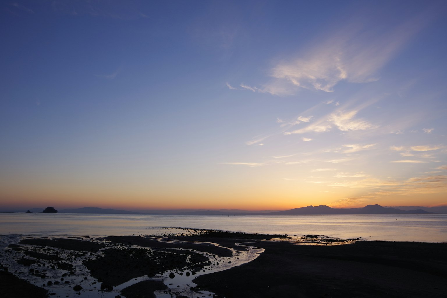 Bellissimo paesaggio con un tramonto sul mare e montagne