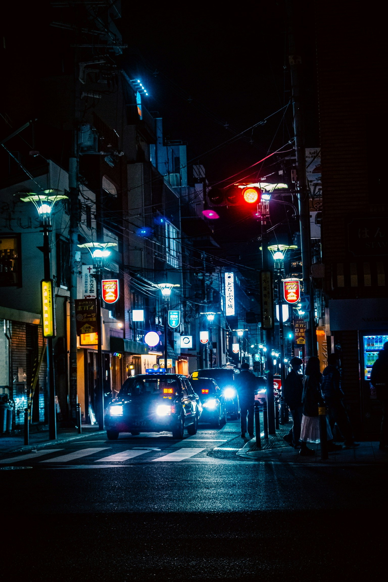 Neon-lit street at night in Osaka with cars