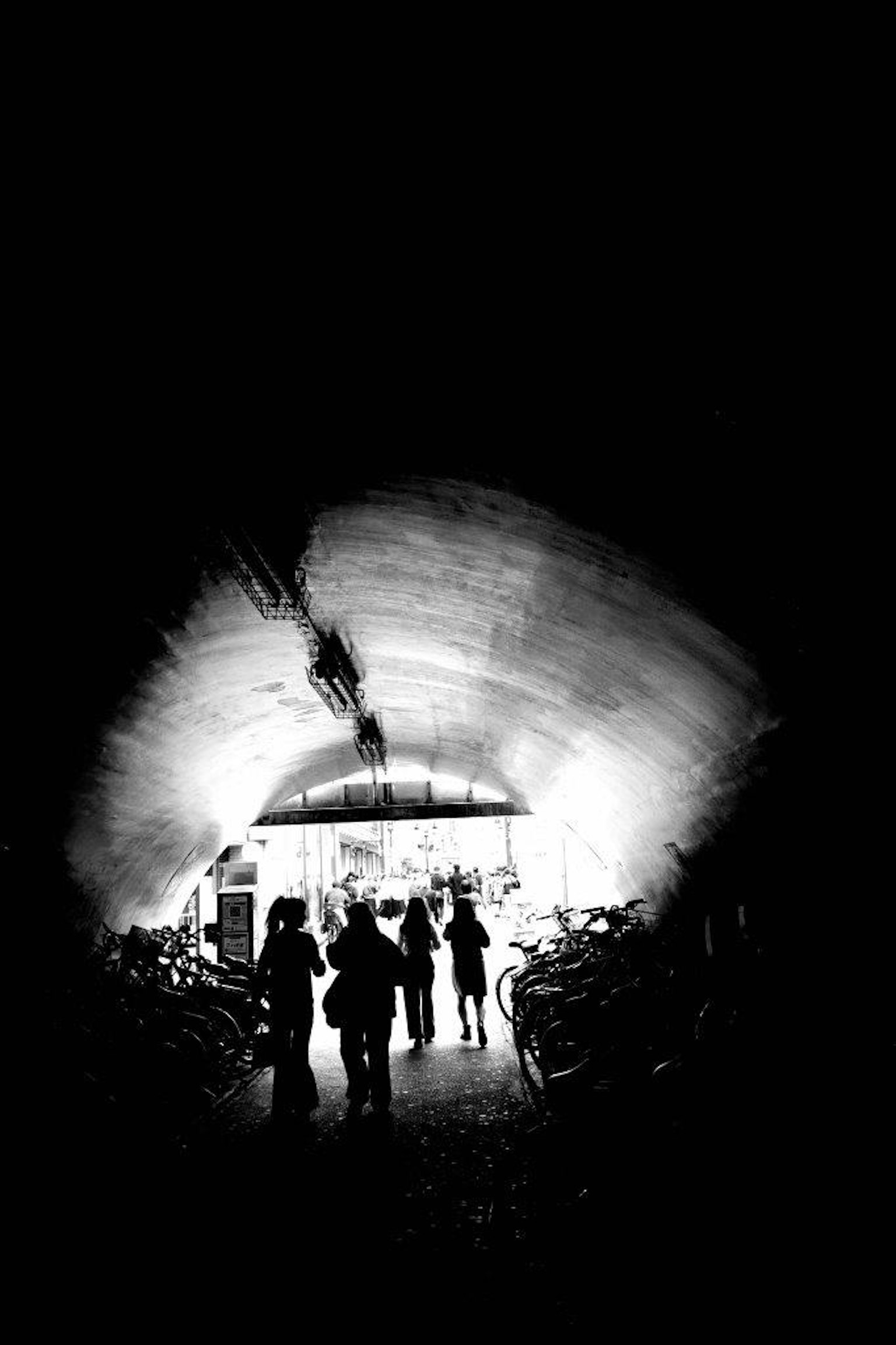 Silhouetten von Menschen, die in einem dunklen Tunnel mit hellem Licht am Ende gehen