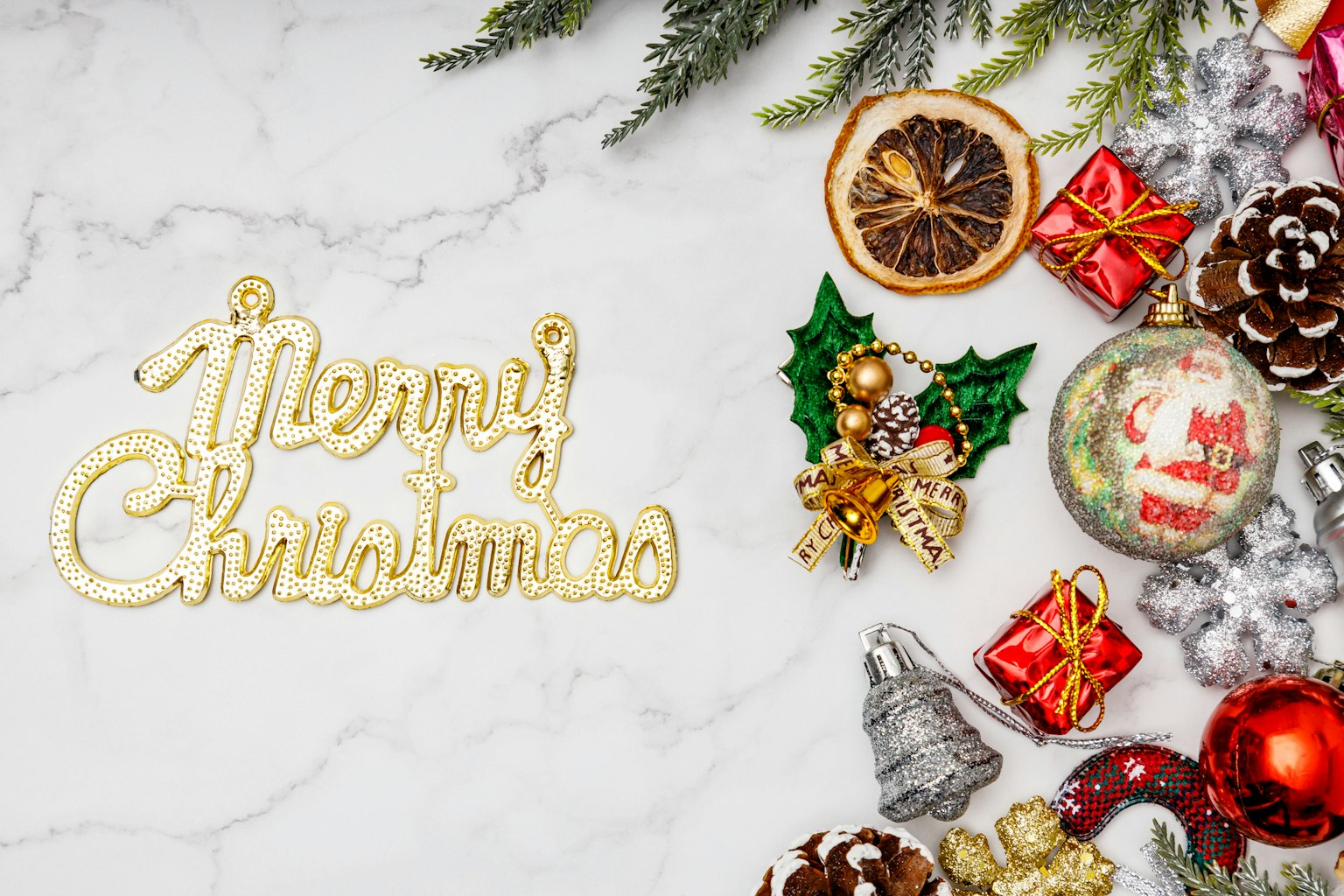 Scritta dorata 'Buon Natale' su una superficie in marmo bianco con decorazioni festive