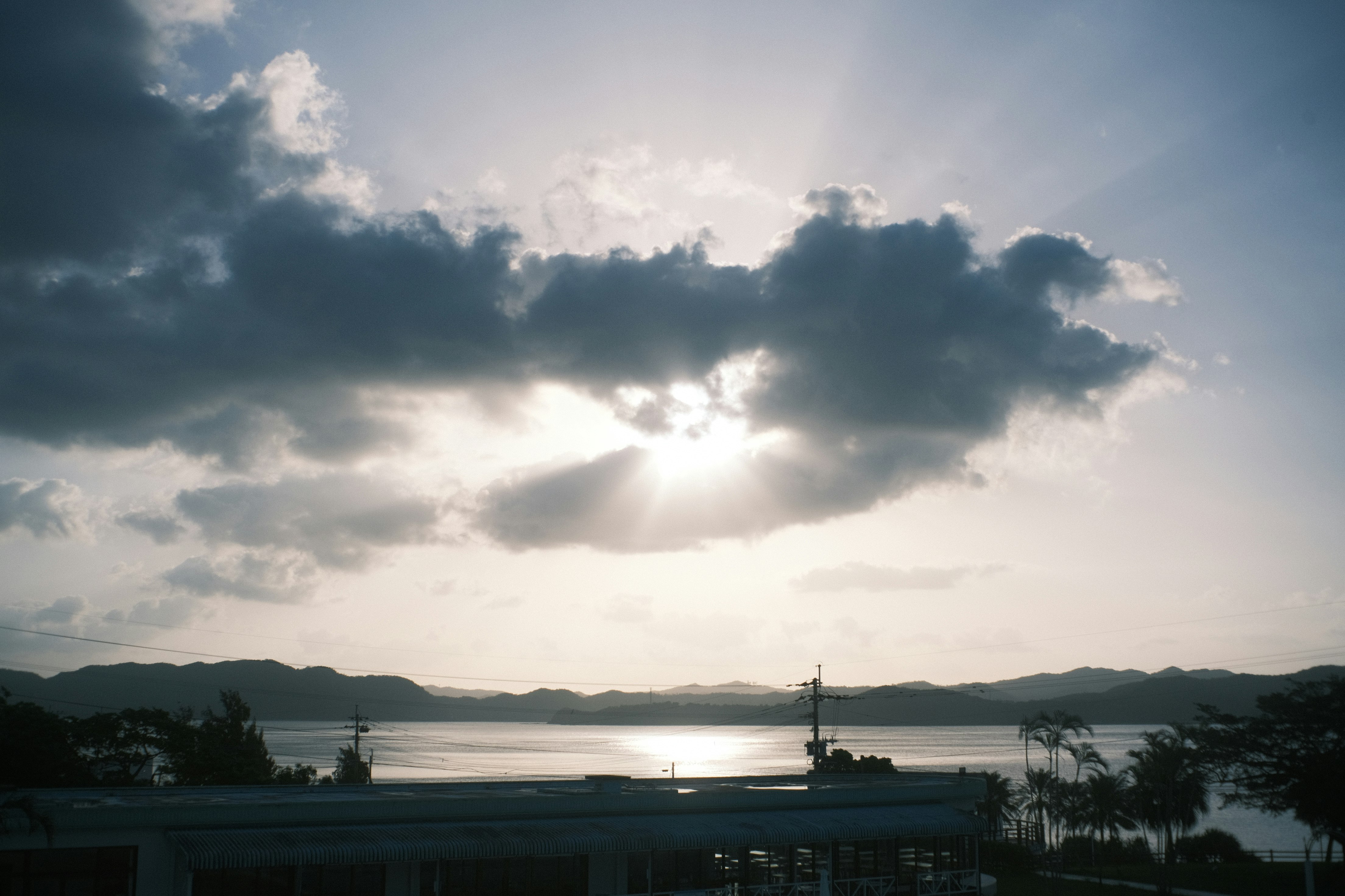 夕暮れの海と水平線、雲の隙間から差す光