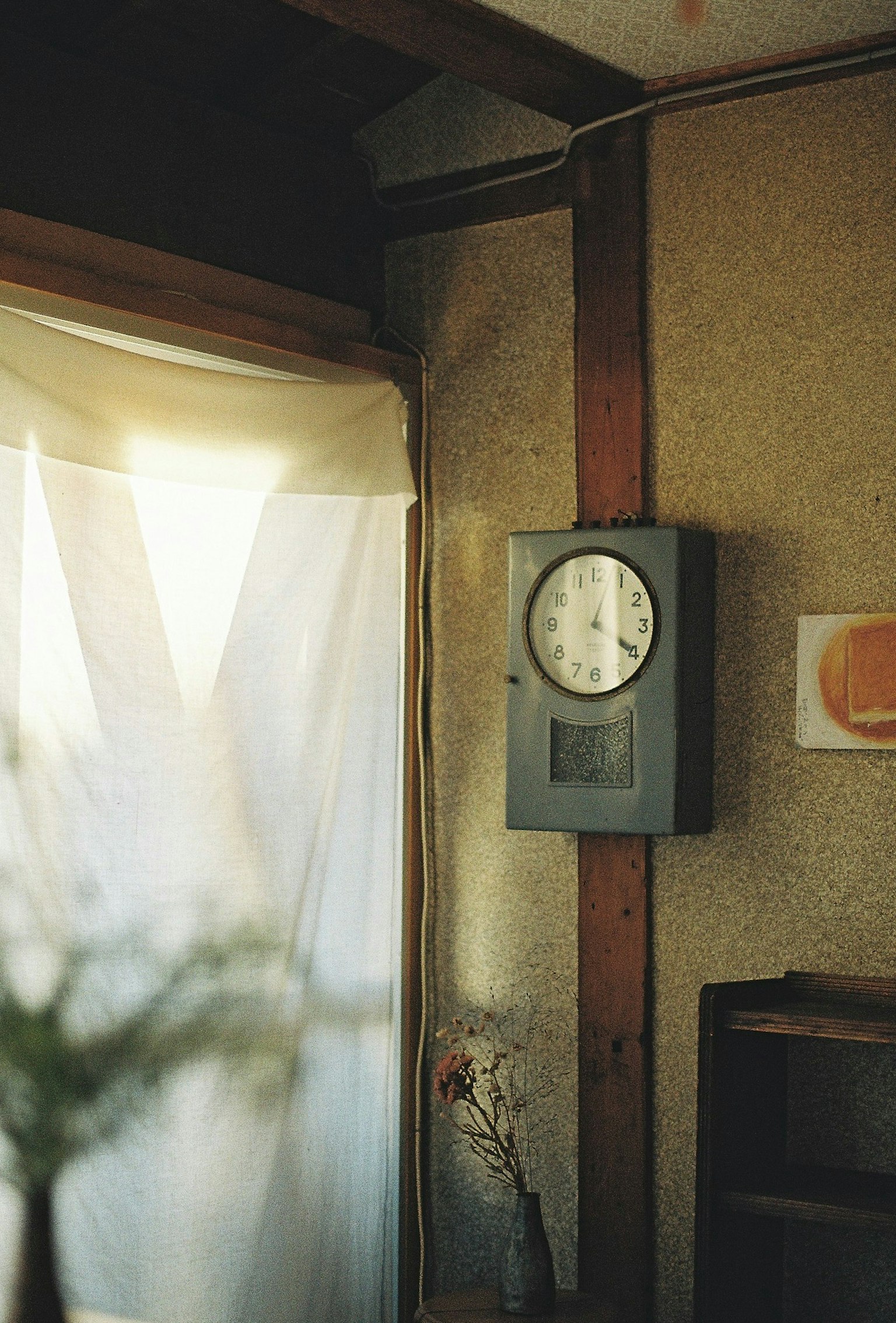 Analog clock on the wall of a simple interior room with white curtains