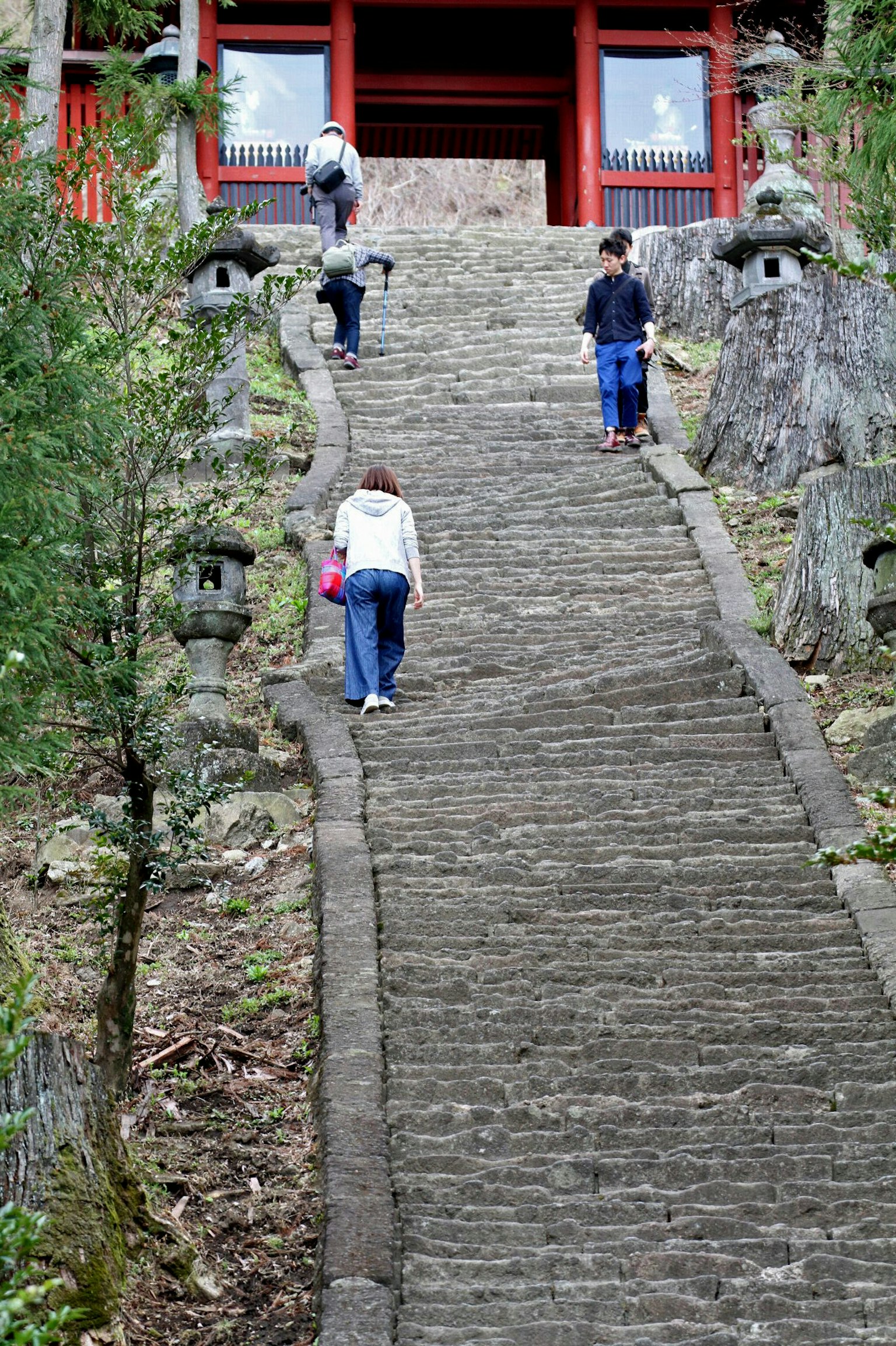 Menschen steigen eine Steintreppe mit Laternen an beiden Seiten hinauf