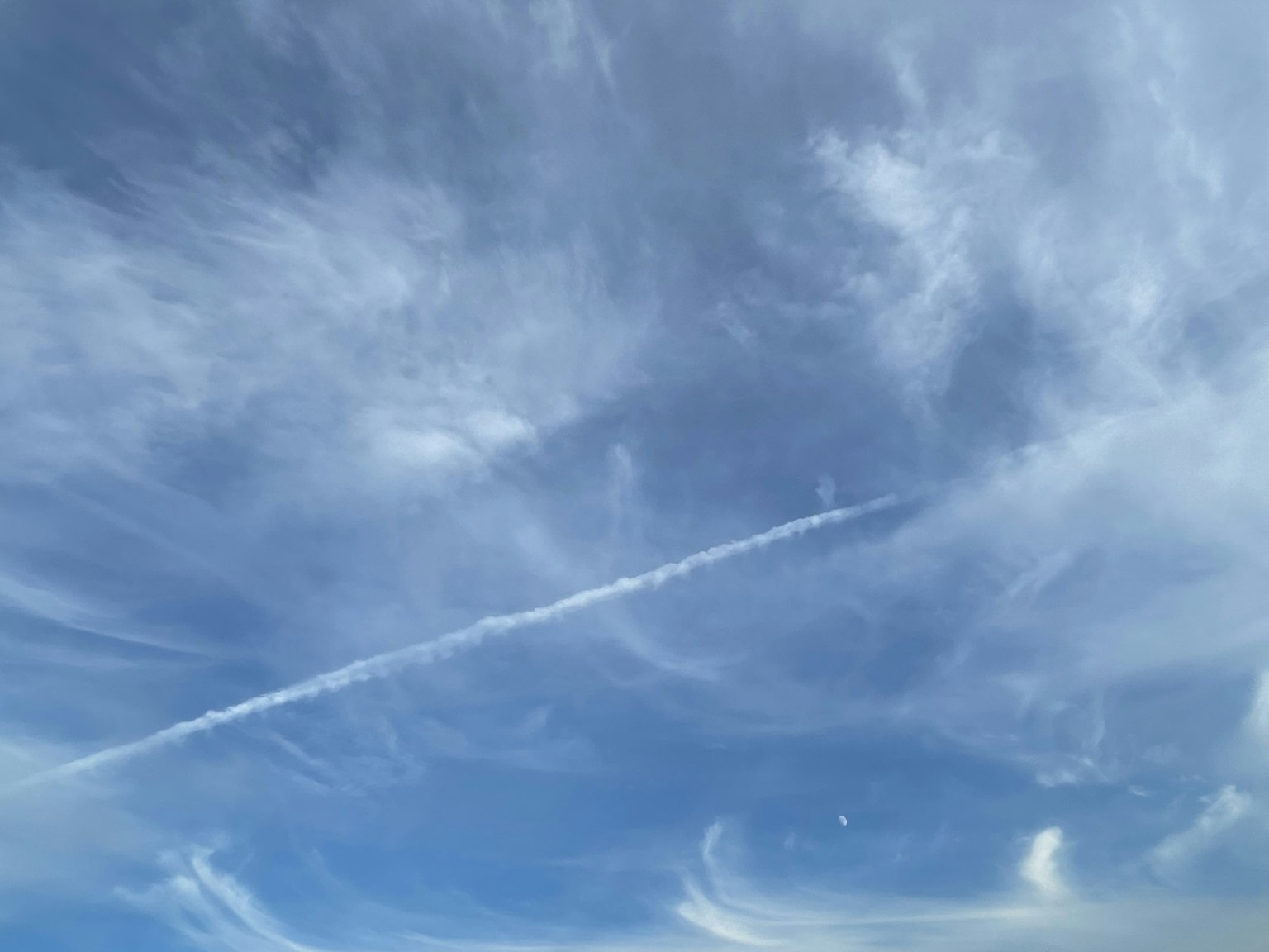 Un ciel bleu avec des nuages légers et un traînée d'avion