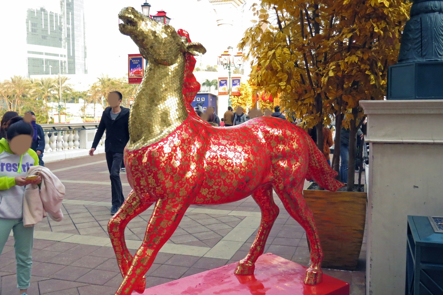 Red and gold horse sculpture stands in a public area