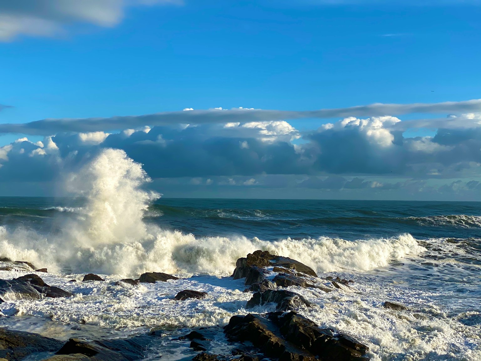 Pemandangan laut dengan langit biru dan ombak yang menghantam