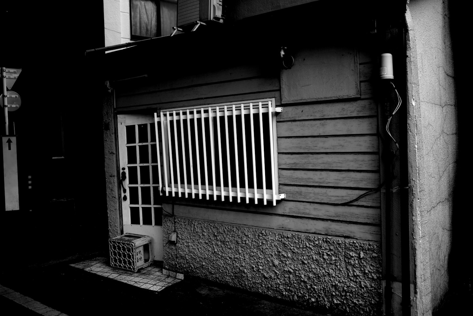 Small black and white building featuring a white barred window