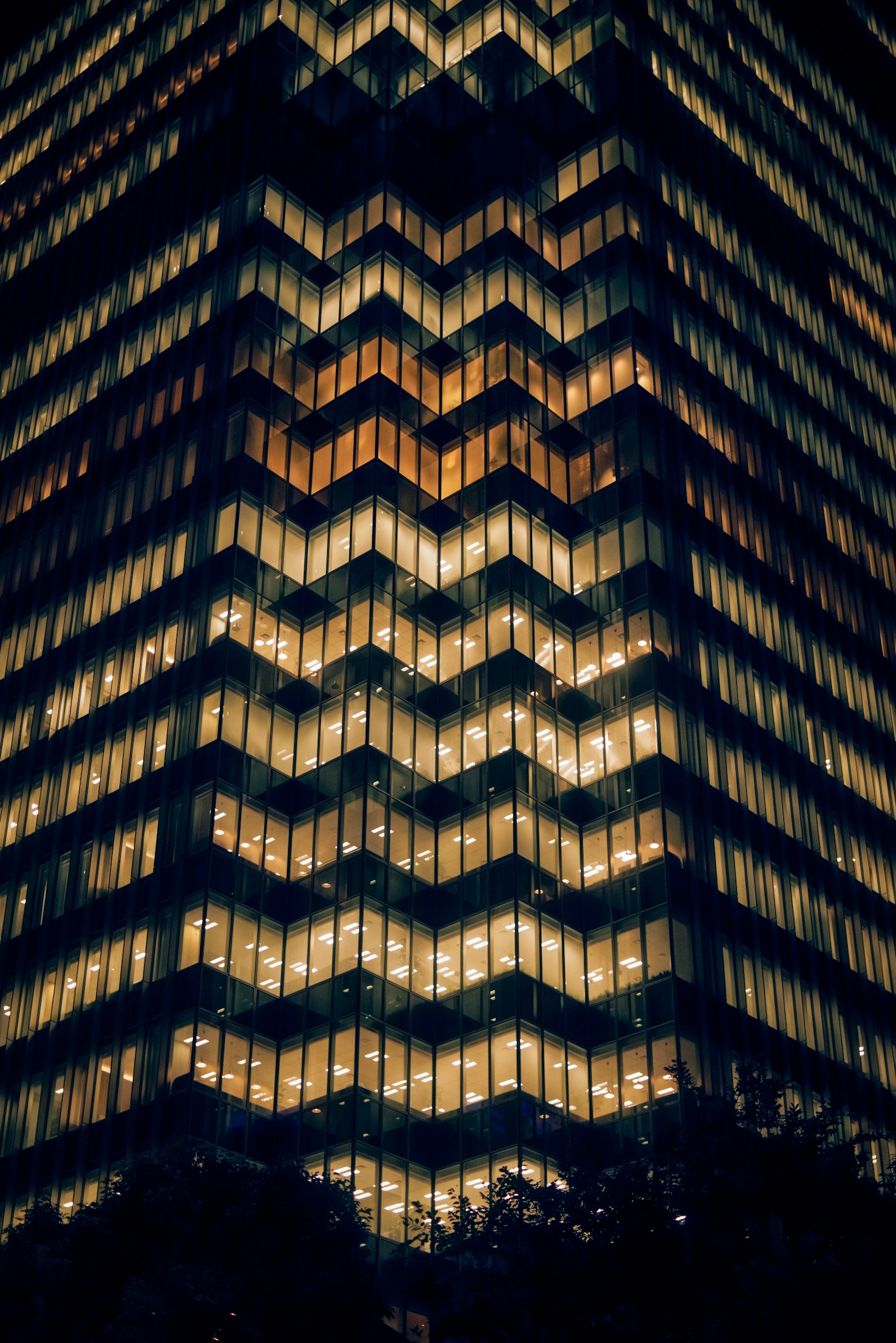 Vista nocturna de un edificio con ventanas iluminadas en patrón zigzagueante
