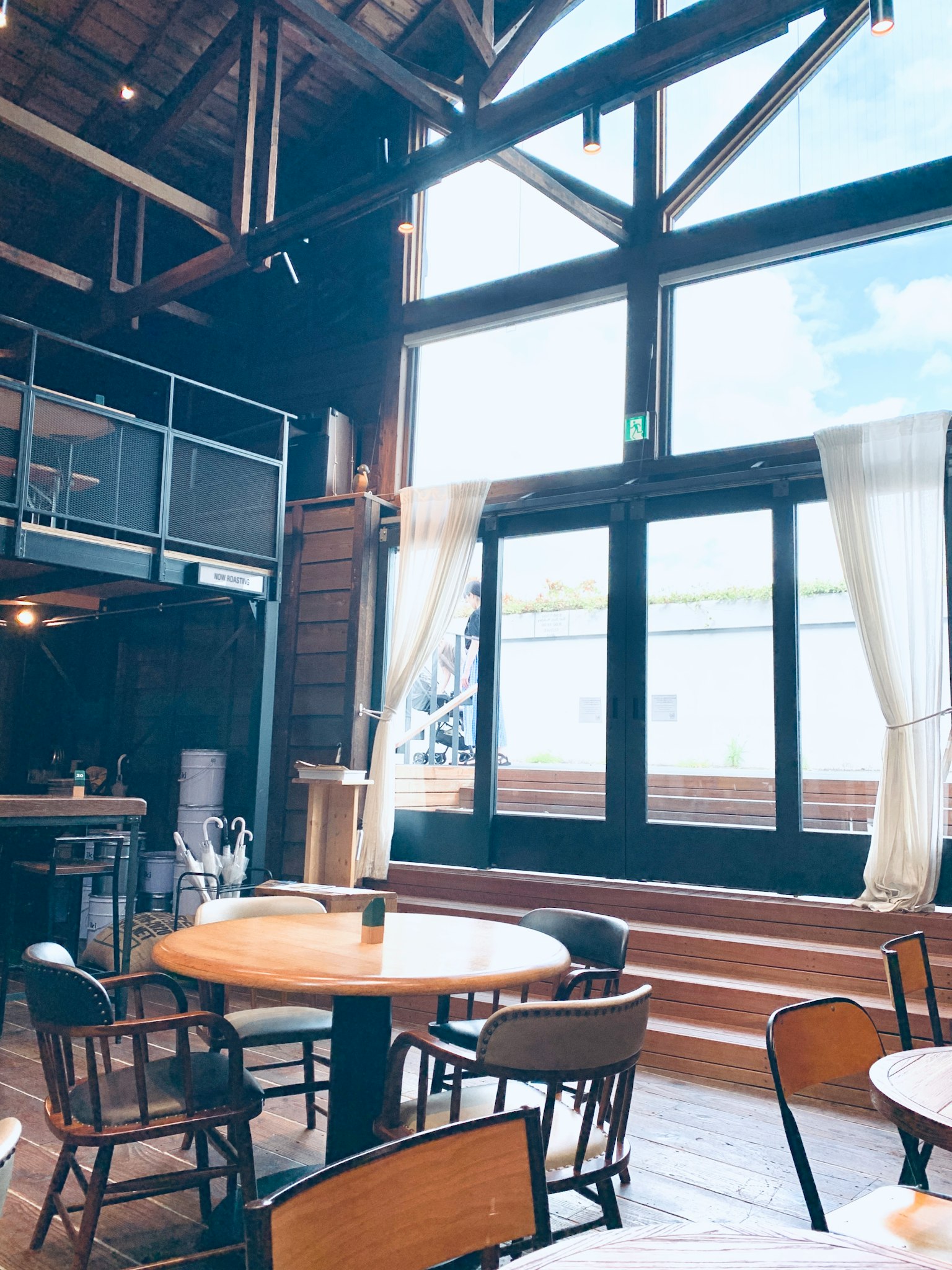 Interior brillante de una cafetería moderna con grandes ventanas mesas y sillas de madera
