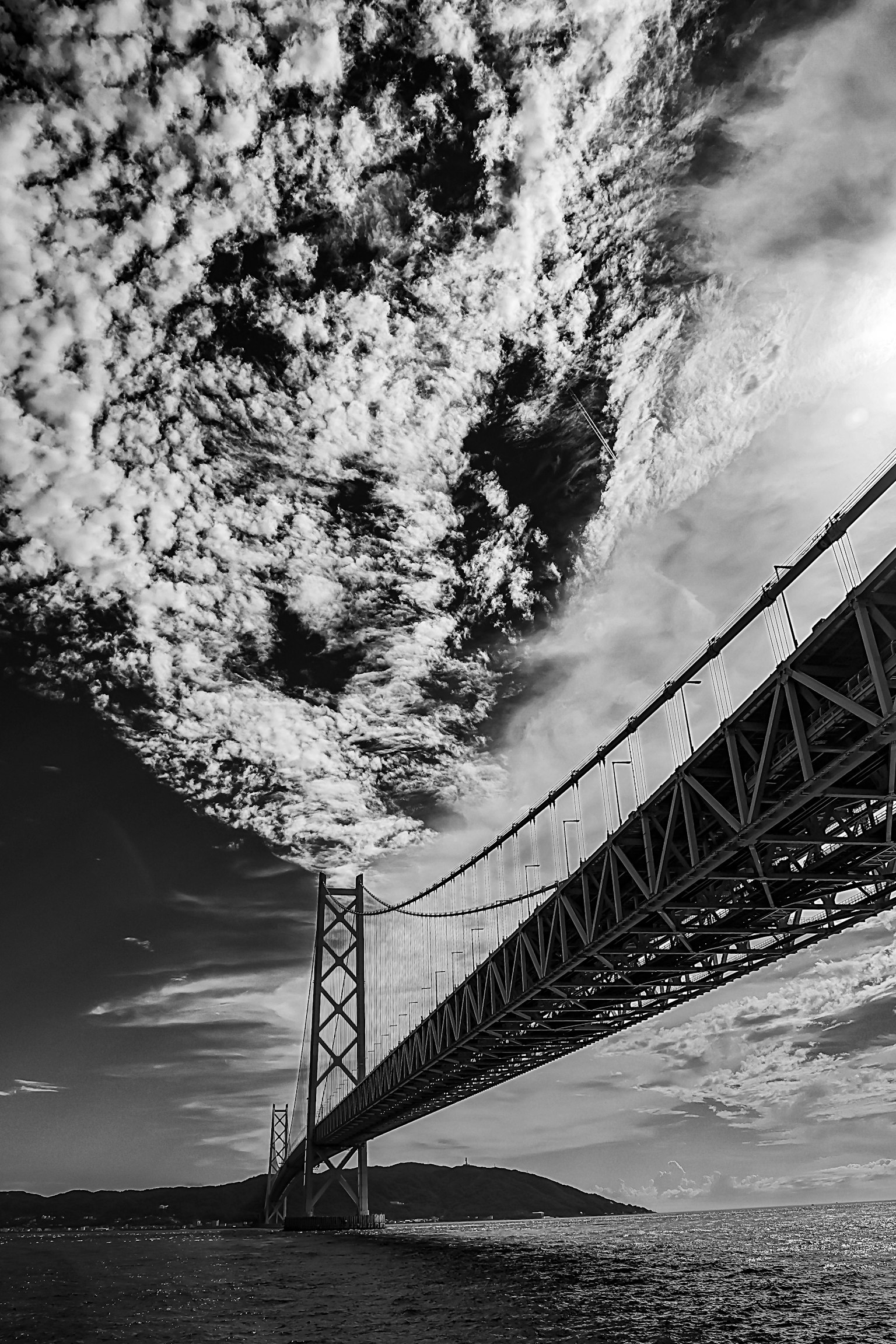 View from below a bridge against a black and white sky showcasing the bridge's structure