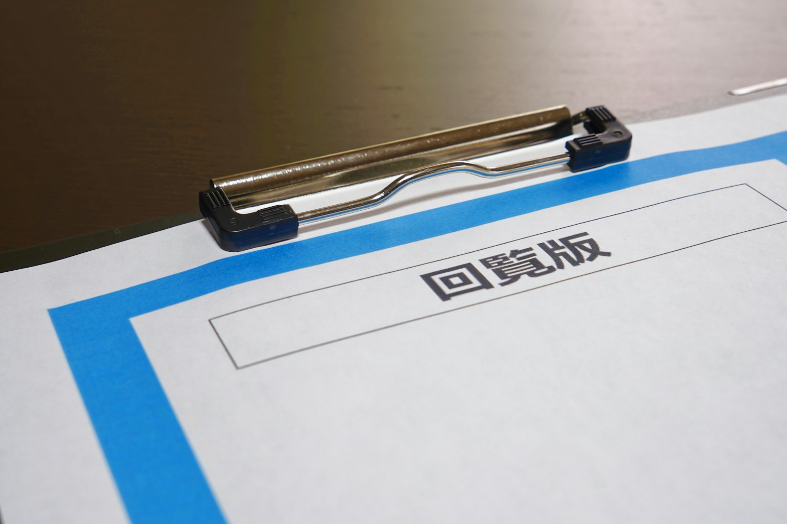 Kertas putih dengan batas biru dan teks kanji Jepang di klip