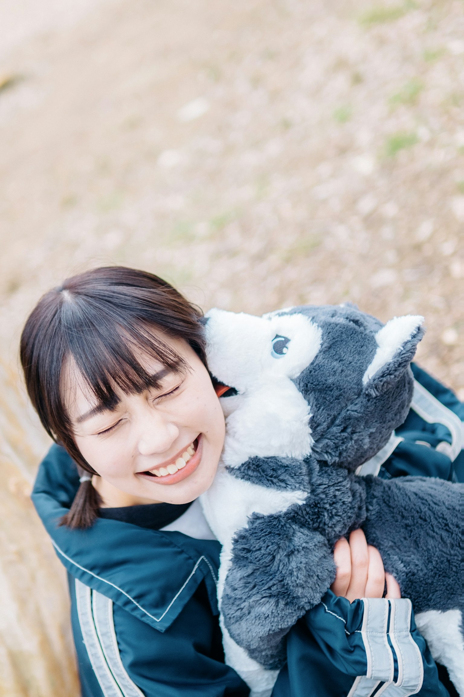 Una mujer sonriendo mientras abraza un peluche de perro gris