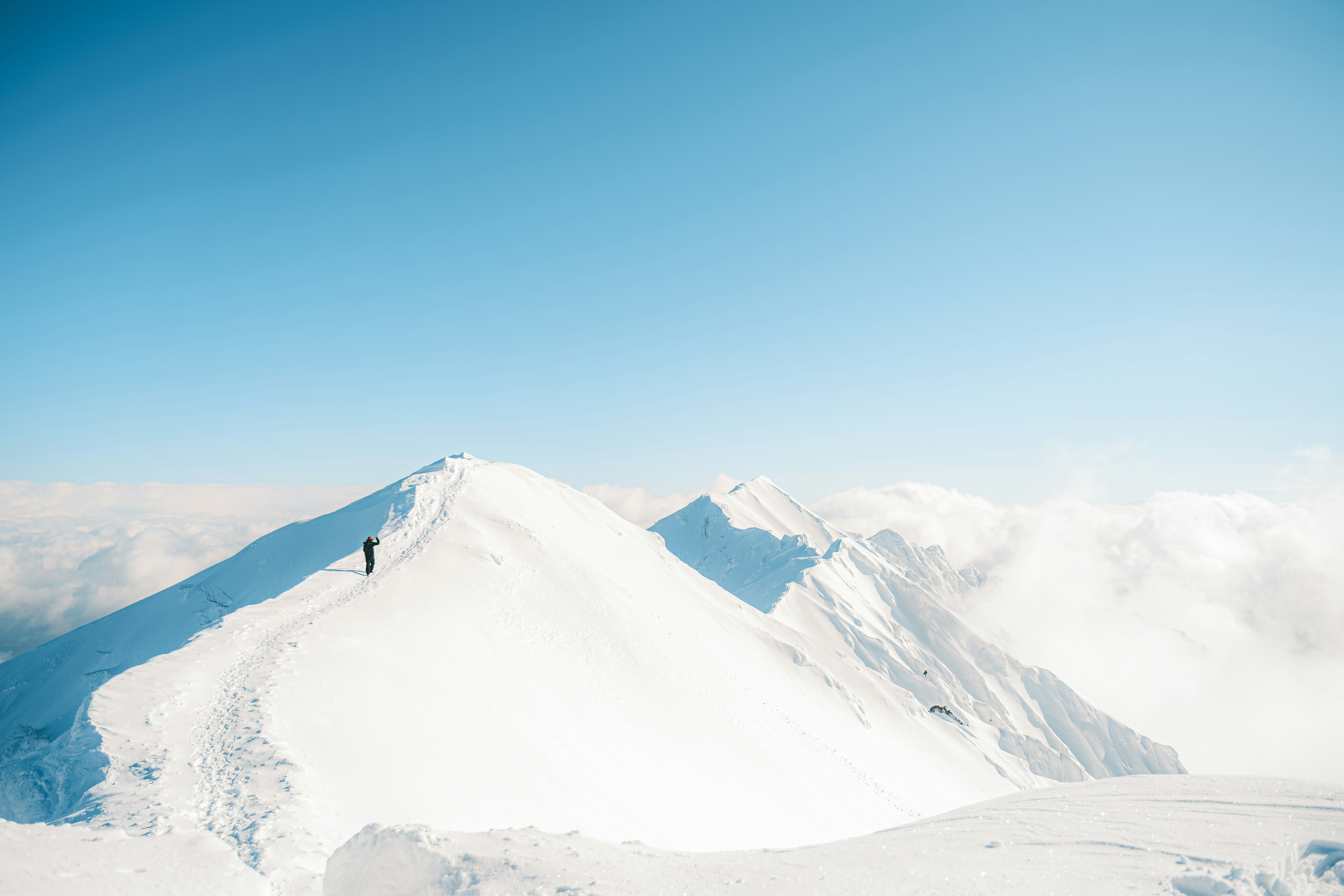 雪の稜線を歩く登山者と遠くの山並み
