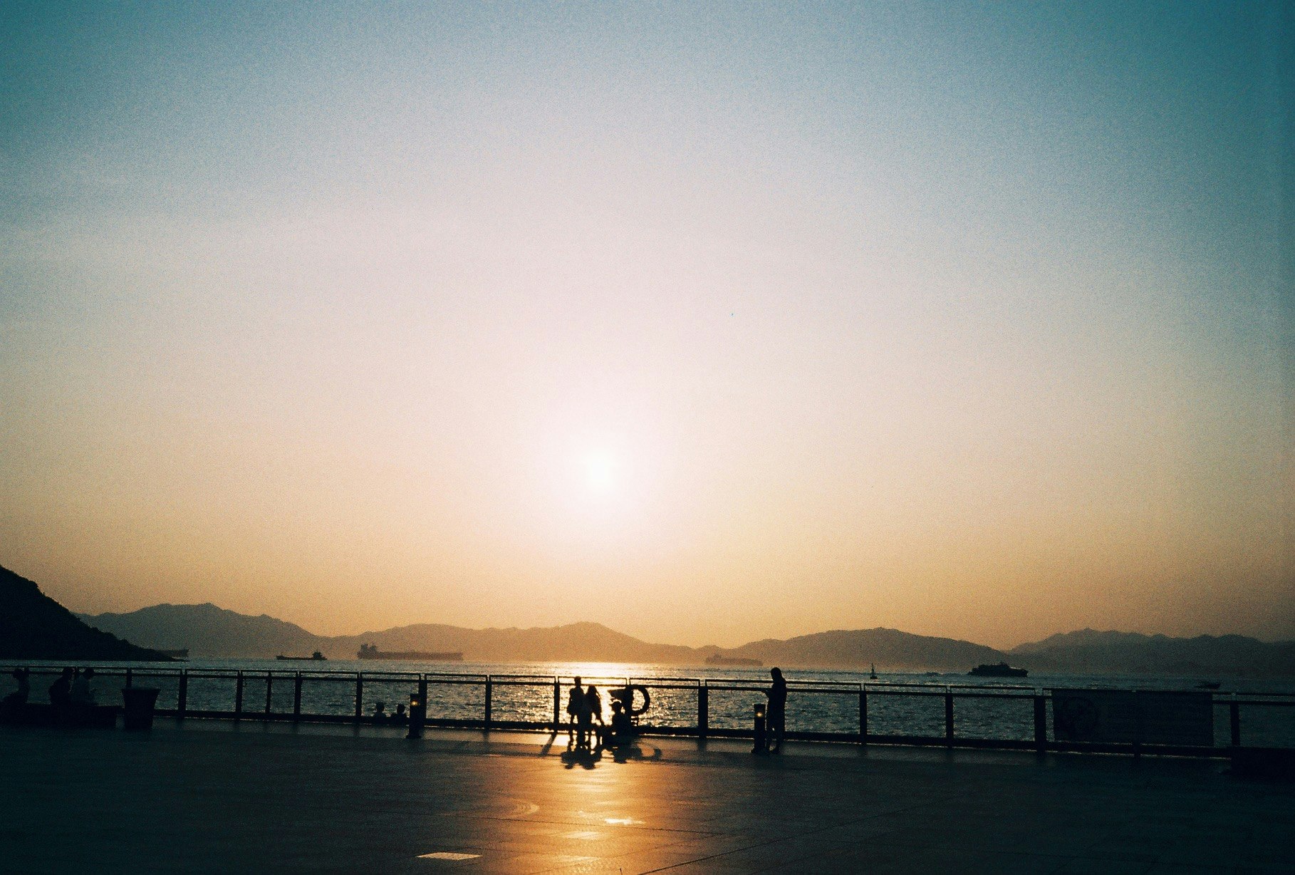 夕日に照らされる海沿いの桟橋と人影