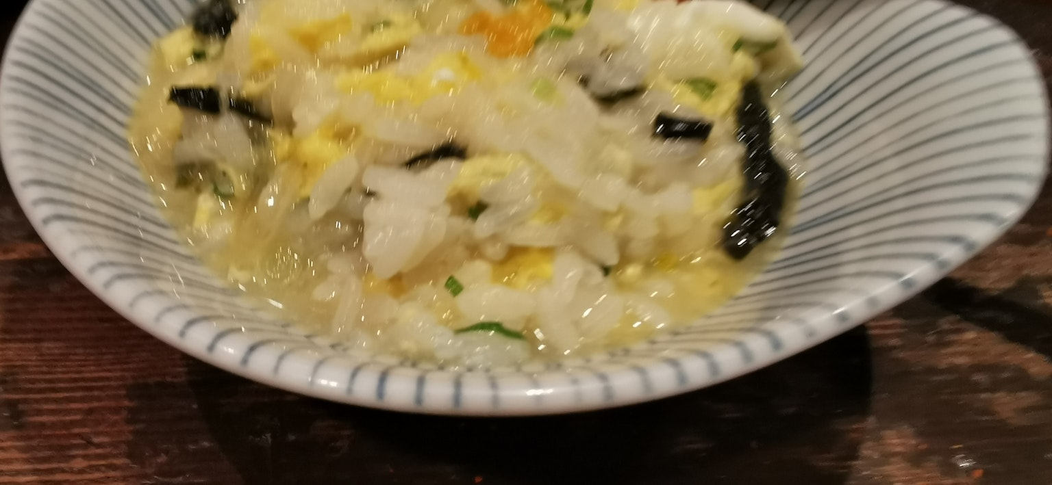 Porridge di riso con uovo e alga in una ciotola bianca
