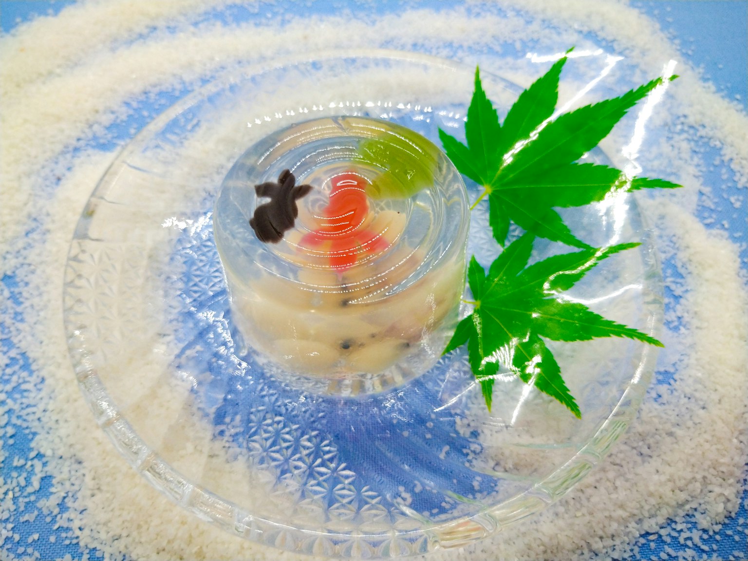 透明甜点上有绿色叶子和红色装饰，背景是白糖